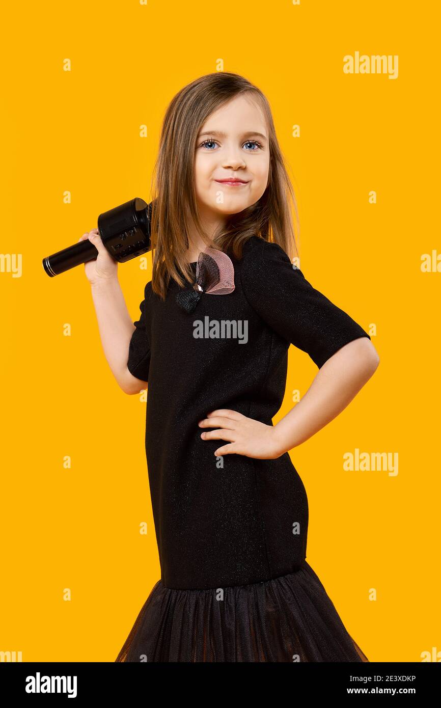 Jeune chanteur avec microphone sans fil sur fond jaune Banque D'Images