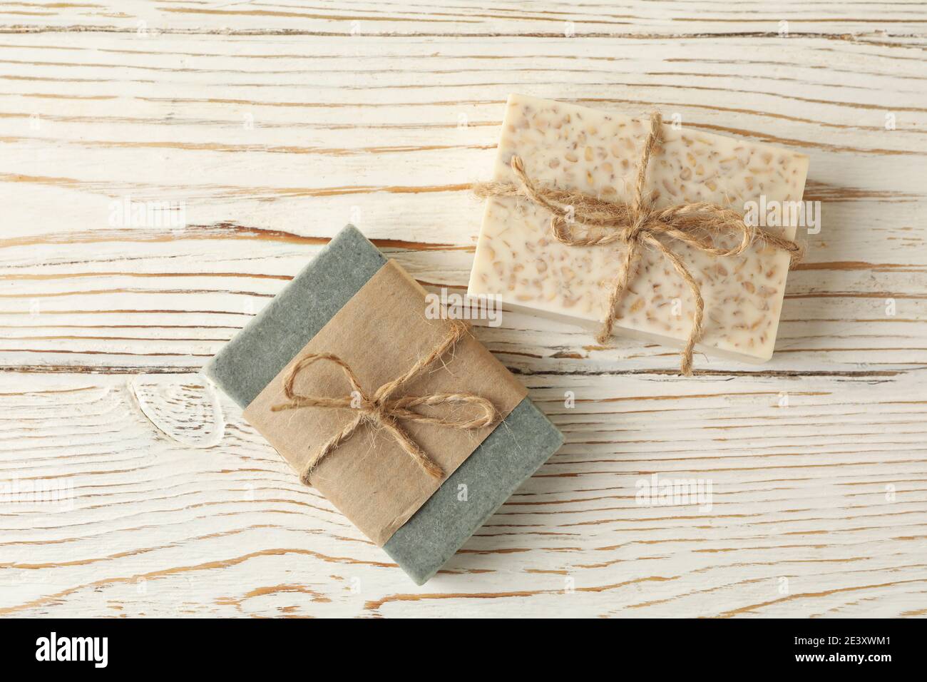 Pièces de savon faites à la main attachées avec une ficelle sur du bois blanc à la lumière douce du jour, un savon naturel rustique au charme artisanal Banque D'Images