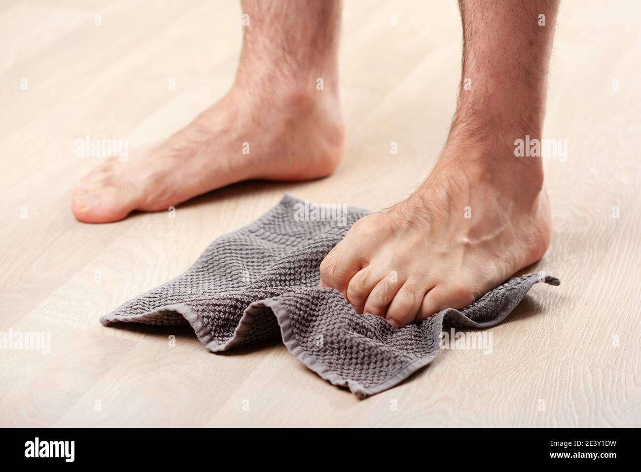 homme faisant la correction des pieds plats exercice gymnastique attrapant la serviette à la maison Banque D'Images