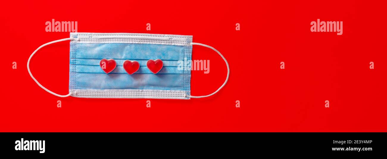 Masque médical bleu avec coeur blanc sur fond rouge. Saint-Valentin jour 2021 Banque D'Images