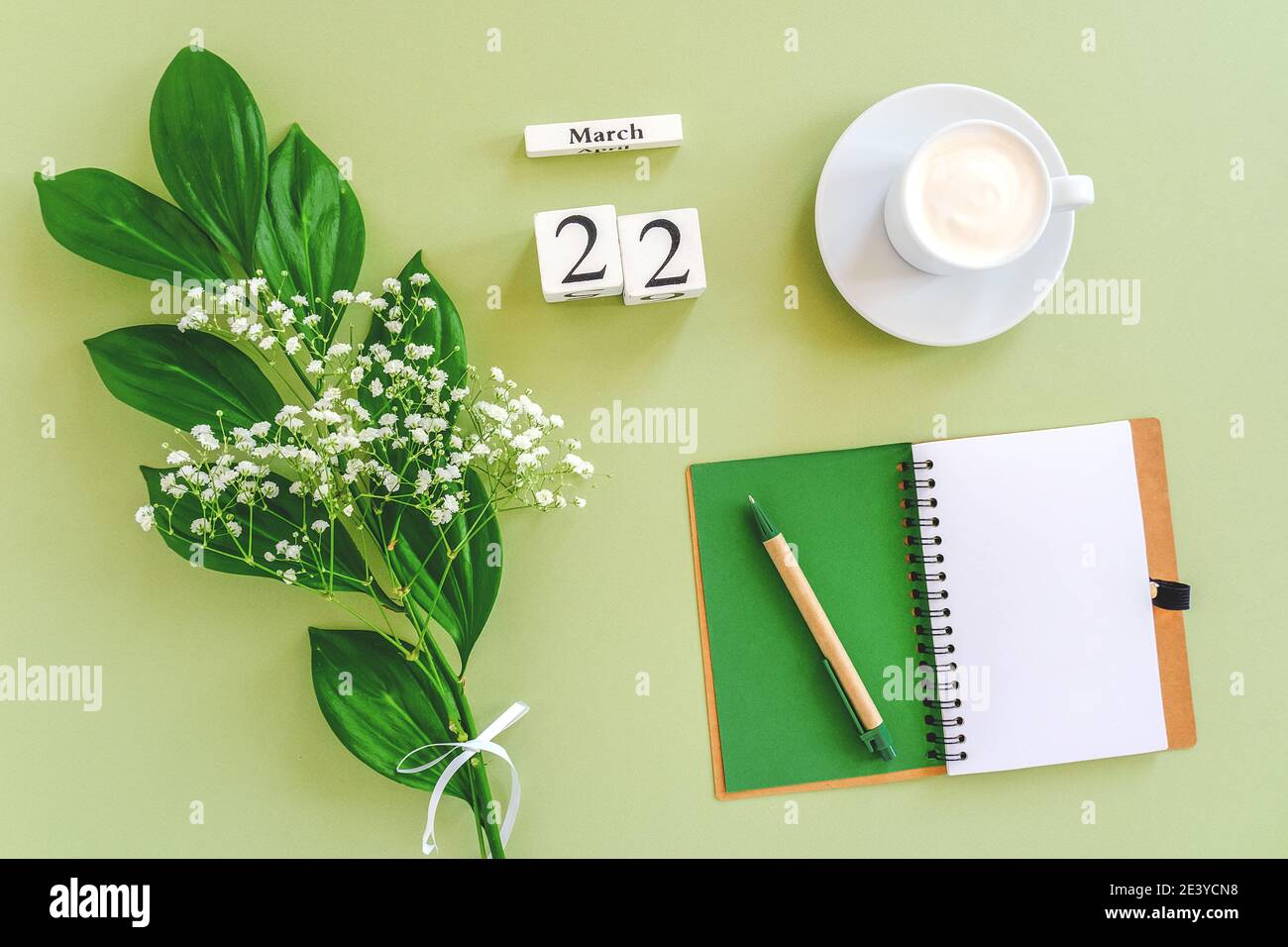 Calendrier des cubes en bois Mars 22. Bloc-notes, tasse de café, bouquet de fleurs sur fond vert. Concept Hello Spring Creative vue du dessus maquette de pose plate. Banque D'Images