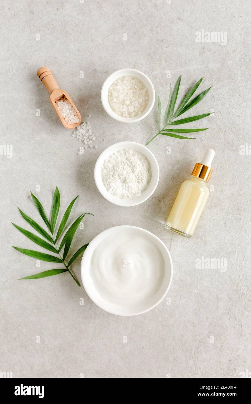 Ensemble de produits cosmétiques pour les soins de la peau et du corps féminins : crème pour le visage, argile cosmétique, sel de mer, bouteille hyaluronique sur fond de marbre gris. Banque D'Images