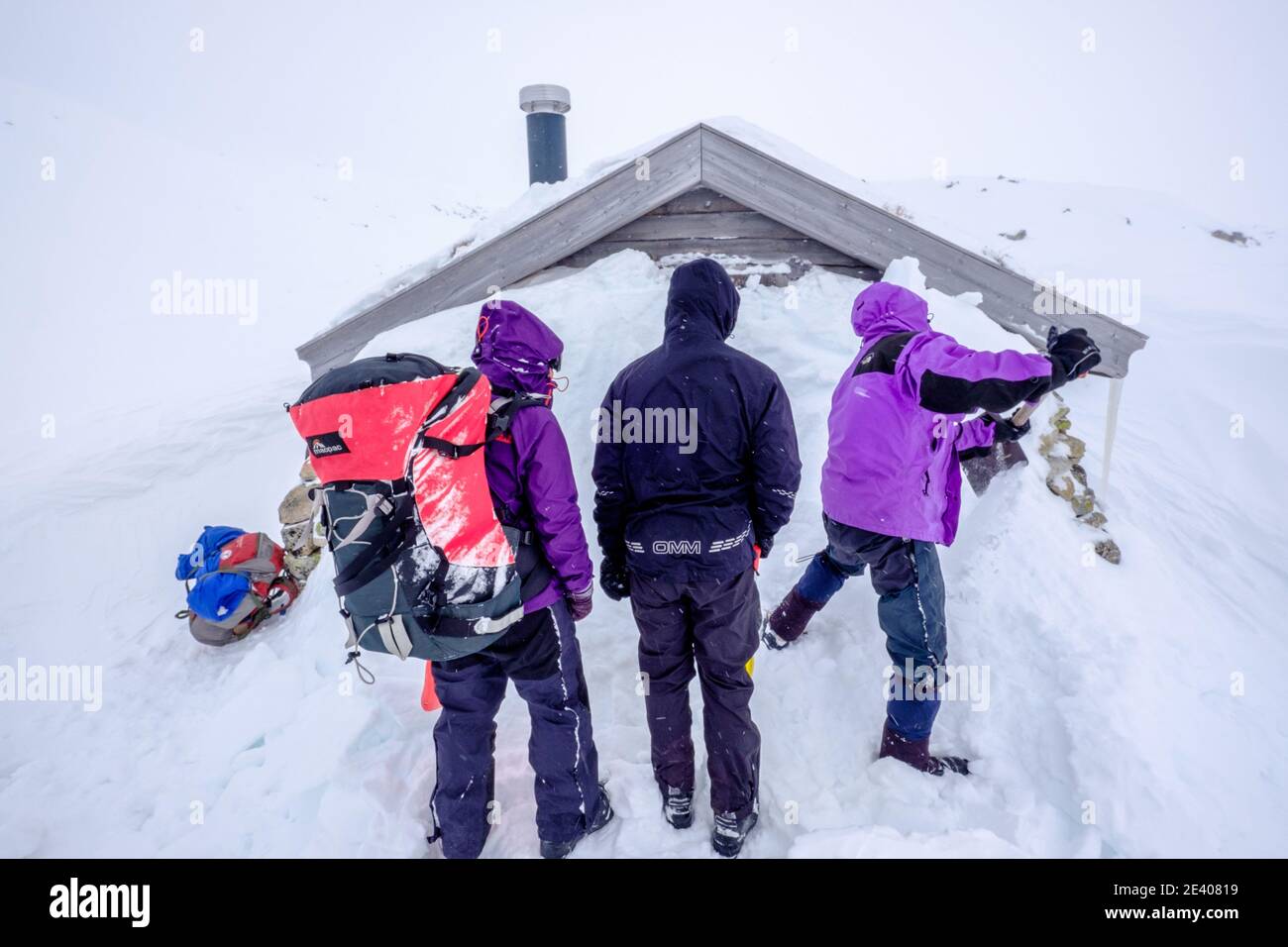 Skieurs lors d'une expédition de ski de randonnée qui creusent la neige Hutte liée dans les montagnes de Norvège Banque D'Images