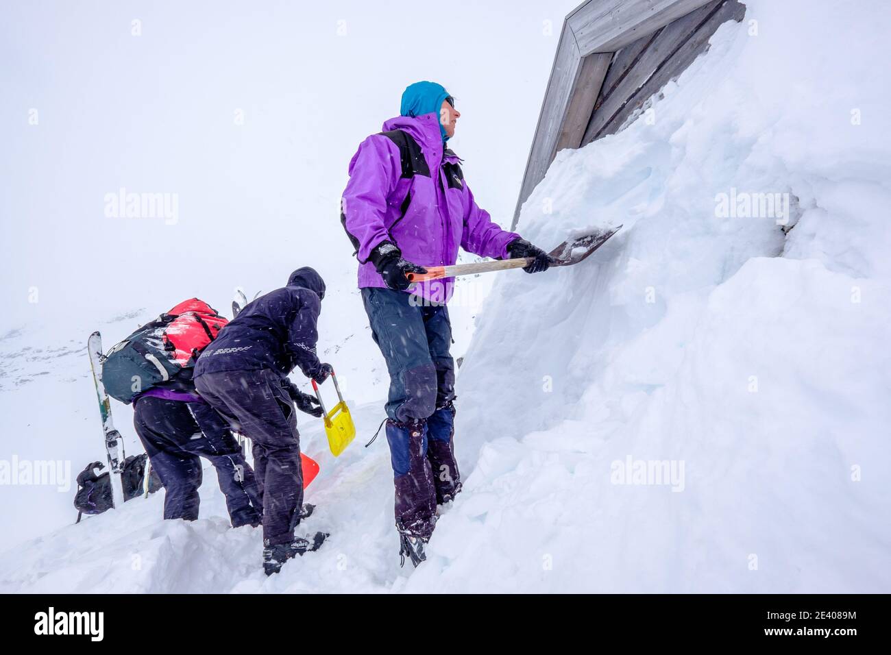 Skieurs lors d'une expédition de ski de randonnée qui creusent la neige Hutte liée dans les montagnes de Norvège Banque D'Images