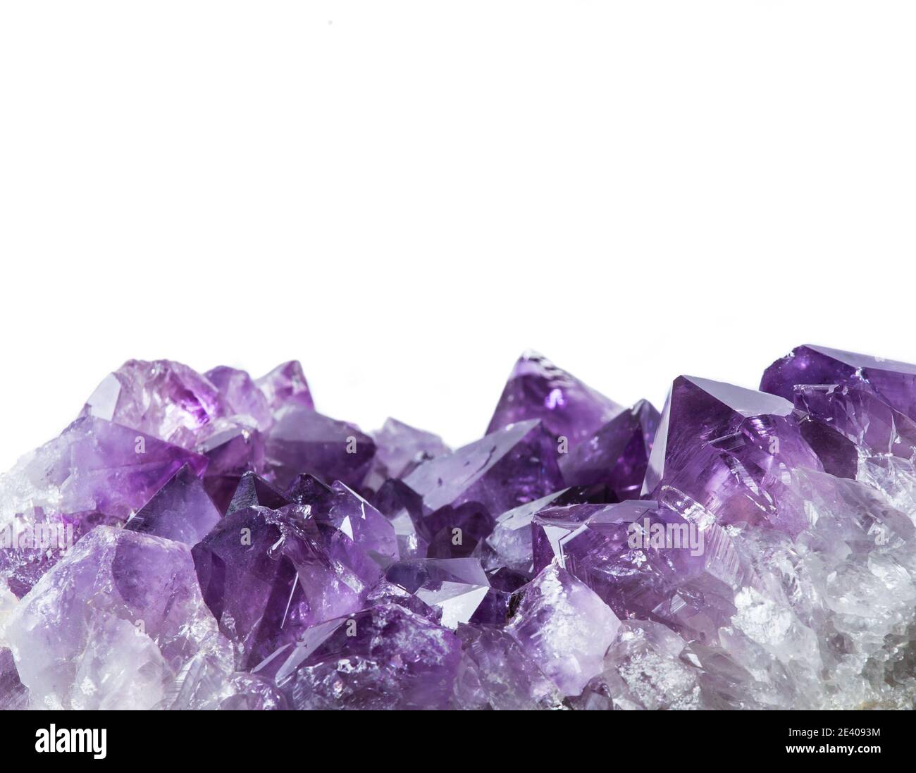 Vue rapprochée de la bordure du grand amas de cristaux d'améthyste violet isolée sur fond blanc. Concept d'arrière-plan magique ésotérique. Banque D'Images