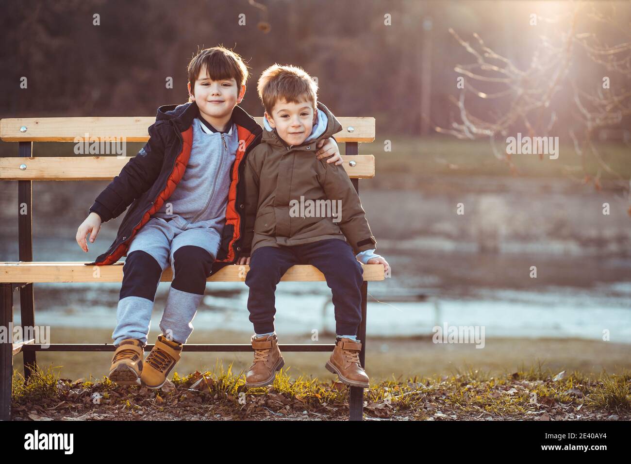 Deux petits garçons, frères, assis sur un banc, affectueux l'un avec l'autre. Copier l'espace Banque D'Images