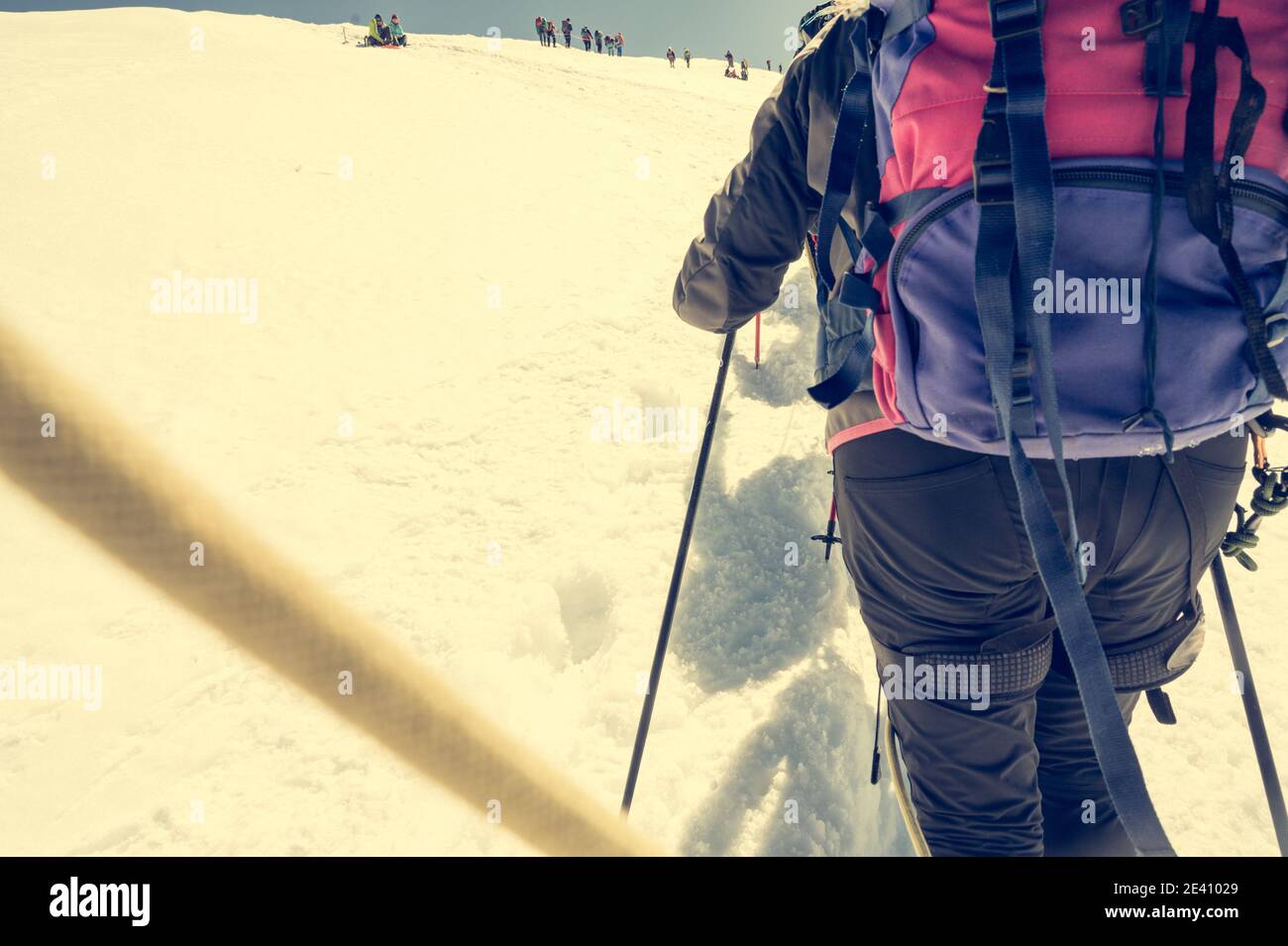 Point de vue du membre de l'équipe de cordage avec les alpinistes marchant sur la neige et la glace par temps ensoleillé. Banque D'Images