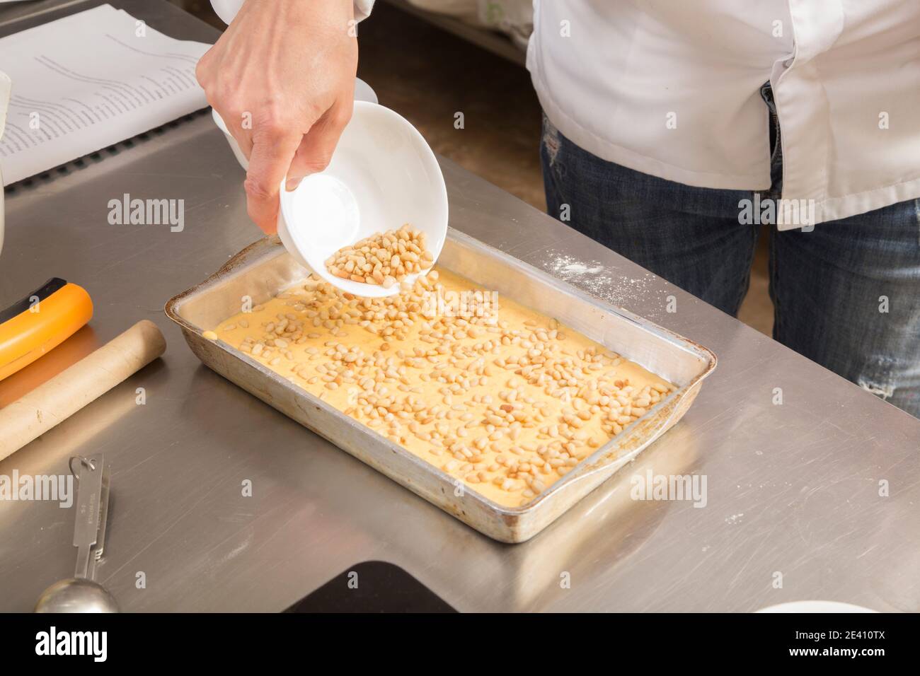 Un tas de pignons de pin sur la pâte dans un plat de cuisson. Le processus de fabrication de biscuits avec des carottes. Gros plan. Banque D'Images