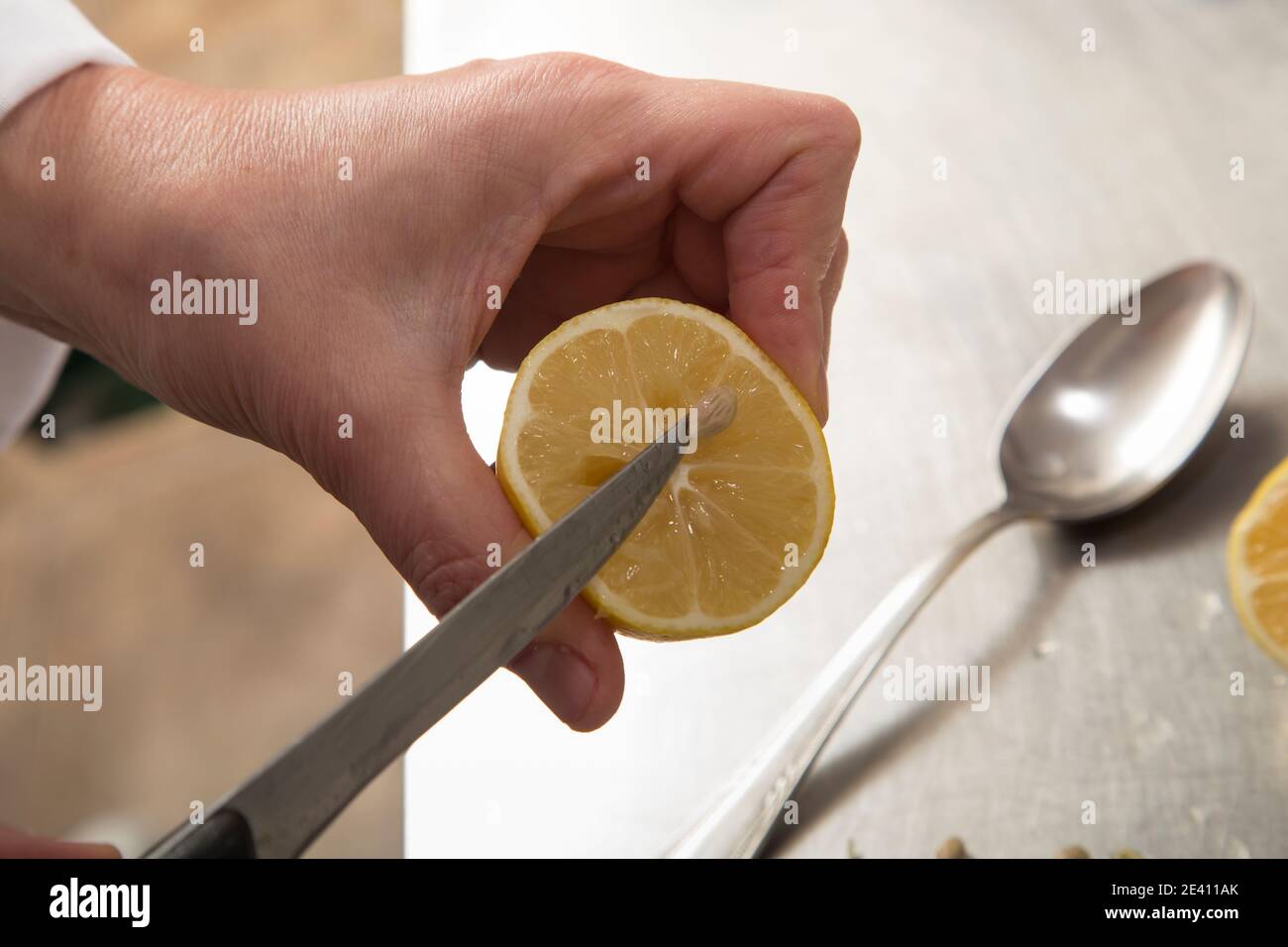 Comment presser le jus de citron. L'arrière-plan est une surface en acier inoxydable. Gros plan. Banque D'Images