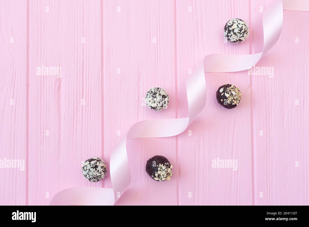 Bonbons faits main au chocolat sur table en bois rose avec ruban de fête avec place pour votre espace de copie de texte Banque D'Images