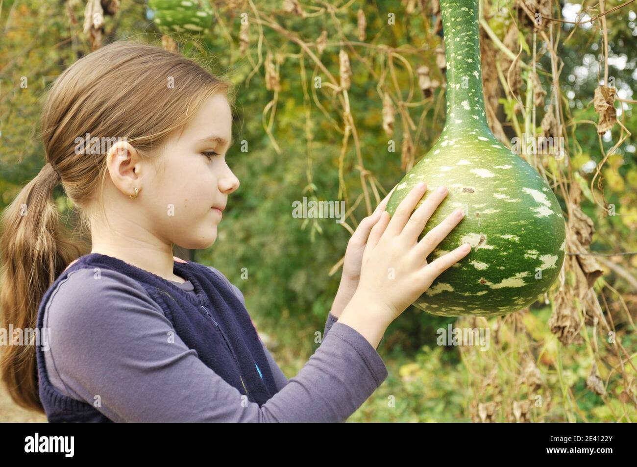 8 ans caucasien enfant, fille, heureux dans le parc, à la recherche au cours d'une grande gourde bouteille Banque D'Images