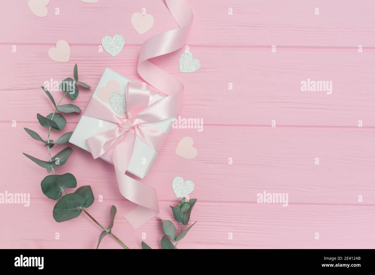 Cadeau de Saint-Valentin ou de mariage, feuilles d'eucalyptus cadre papier coeurs confetti et bois rose fond, espace vide pour votre texte, vue de dessus plat Banque D'Images