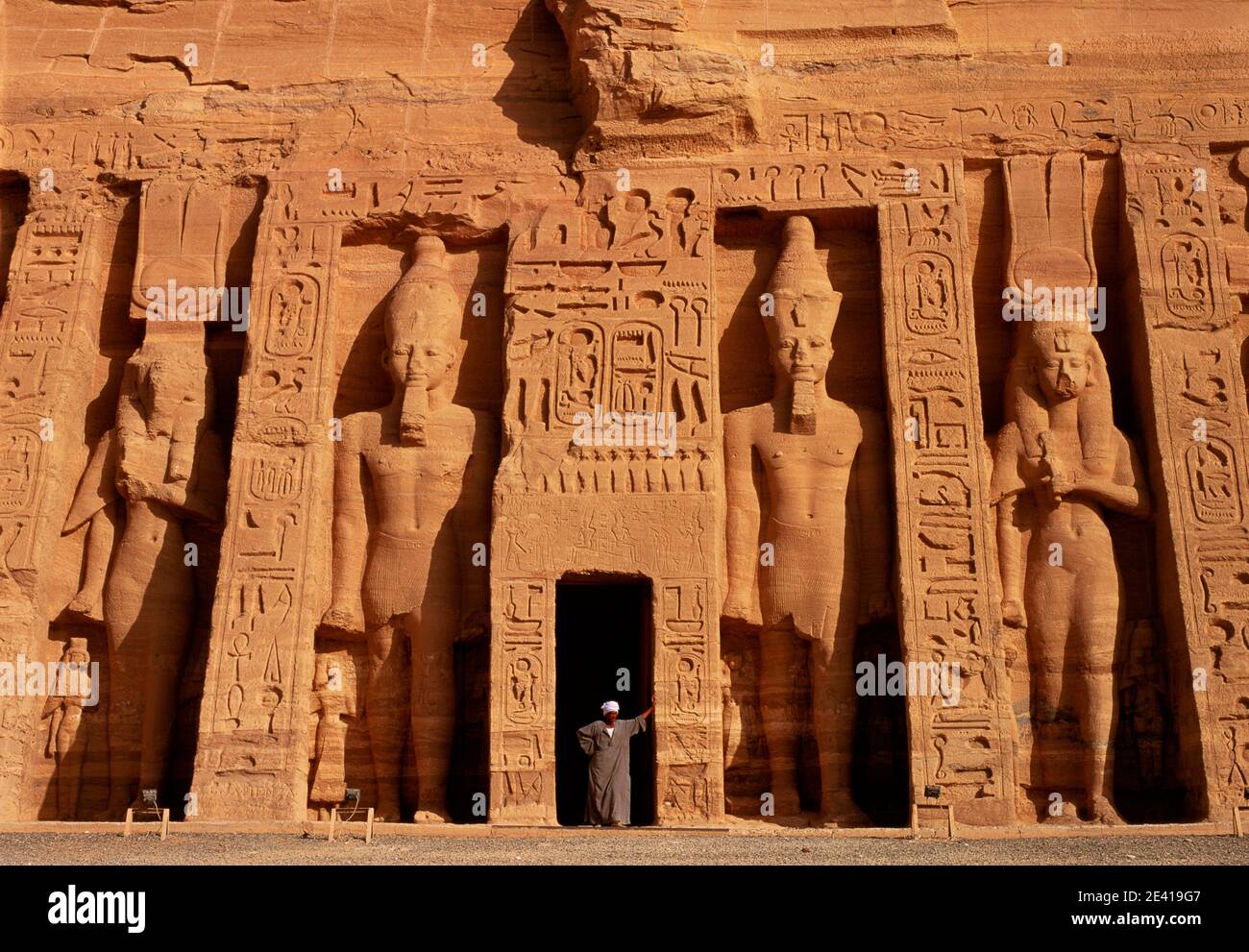 Afrique du Nord Égypte Abu Simbel temple de Hathor Nefertari entrée homme égyptien robe traditionnelle en pierre de porte statues sculptées et hiéroglyphes Banque D'Images