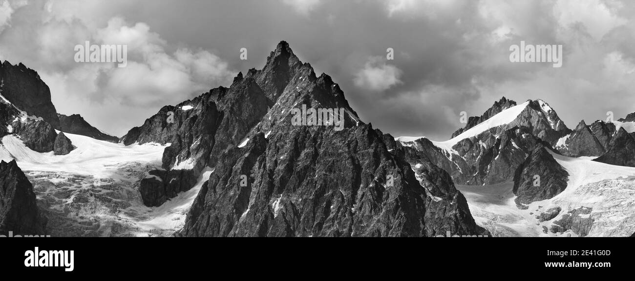 Vue panoramique sur les hautes montagnes enneigées avec glacier et ciel nuageux. Montagnes du Caucase en été. Géorgie, région de Svanetia. Terre noire et blanche Banque D'Images