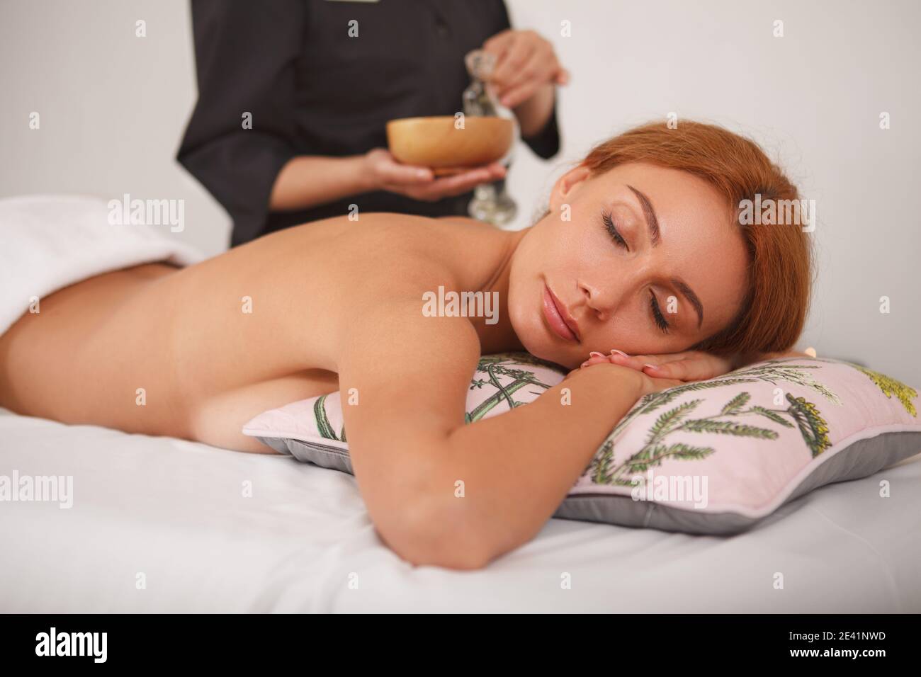 Belle femme heureuse de se faire masser au spa. Femme attrayante allongé  sur une table de massage à la clinique de beauté, masseuse versant de  l'huile de massage dans Photo Stock -