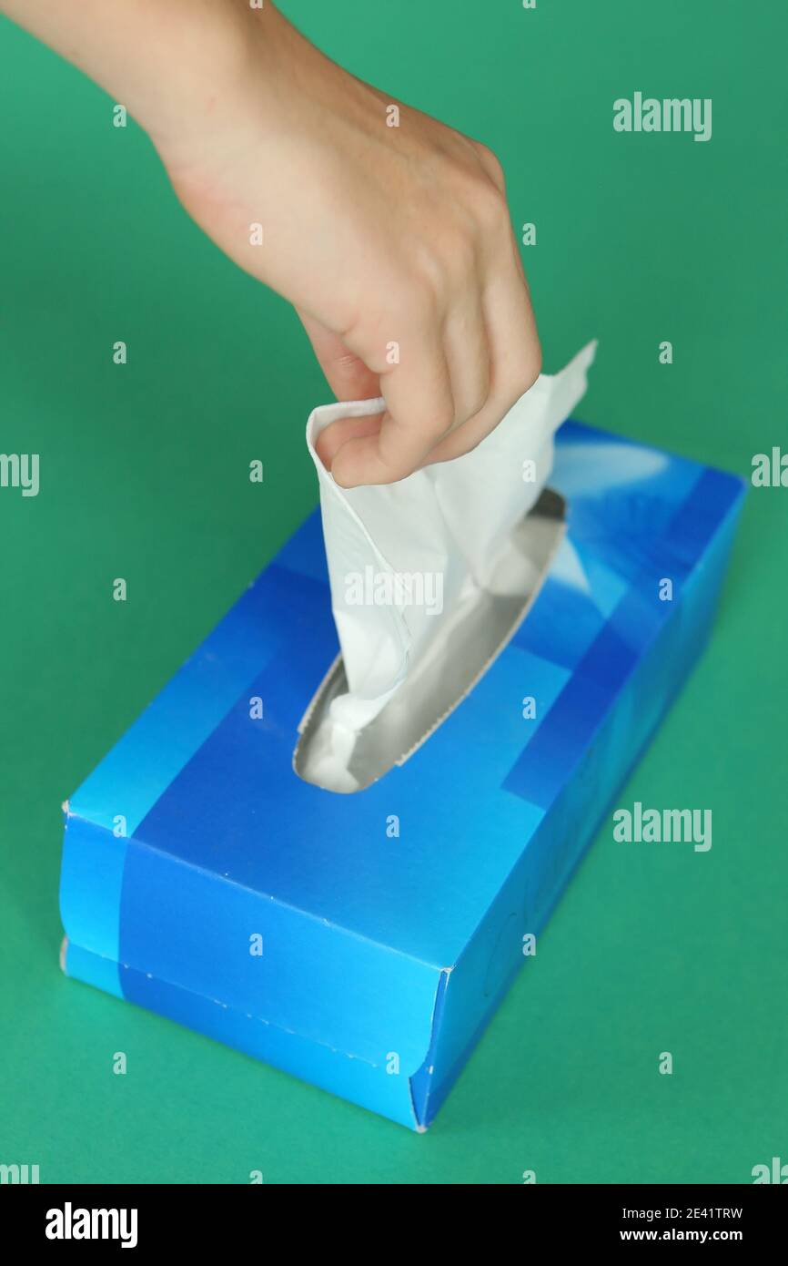 Gros plan de la main d'une femme avec un rhume et malade prenant un tissu blanc d'une boîte bleue, hygiénique et produit de santé Banque D'Images