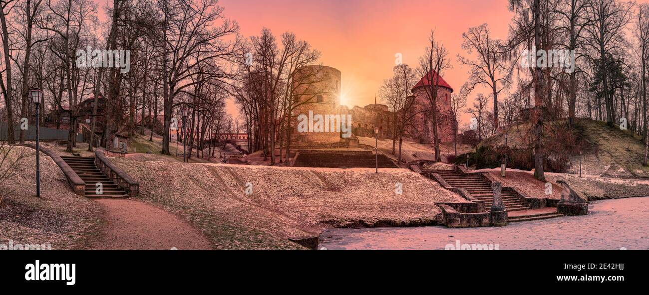 Vue panoramique du coucher de soleil sur le château de Cesis dans un beau parc avec lac gelé et escaliers en pierre à Cesis, Lettonie Banque D'Images