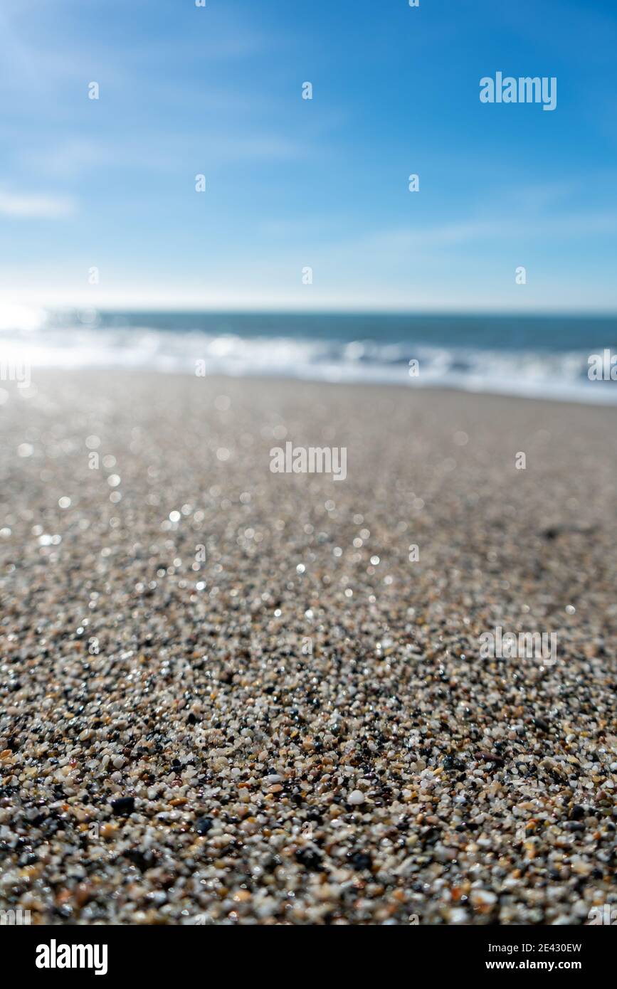 Gros plan de grains de sable sur une plage avec flou littoral et horizon en arrière-plan Banque D'Images