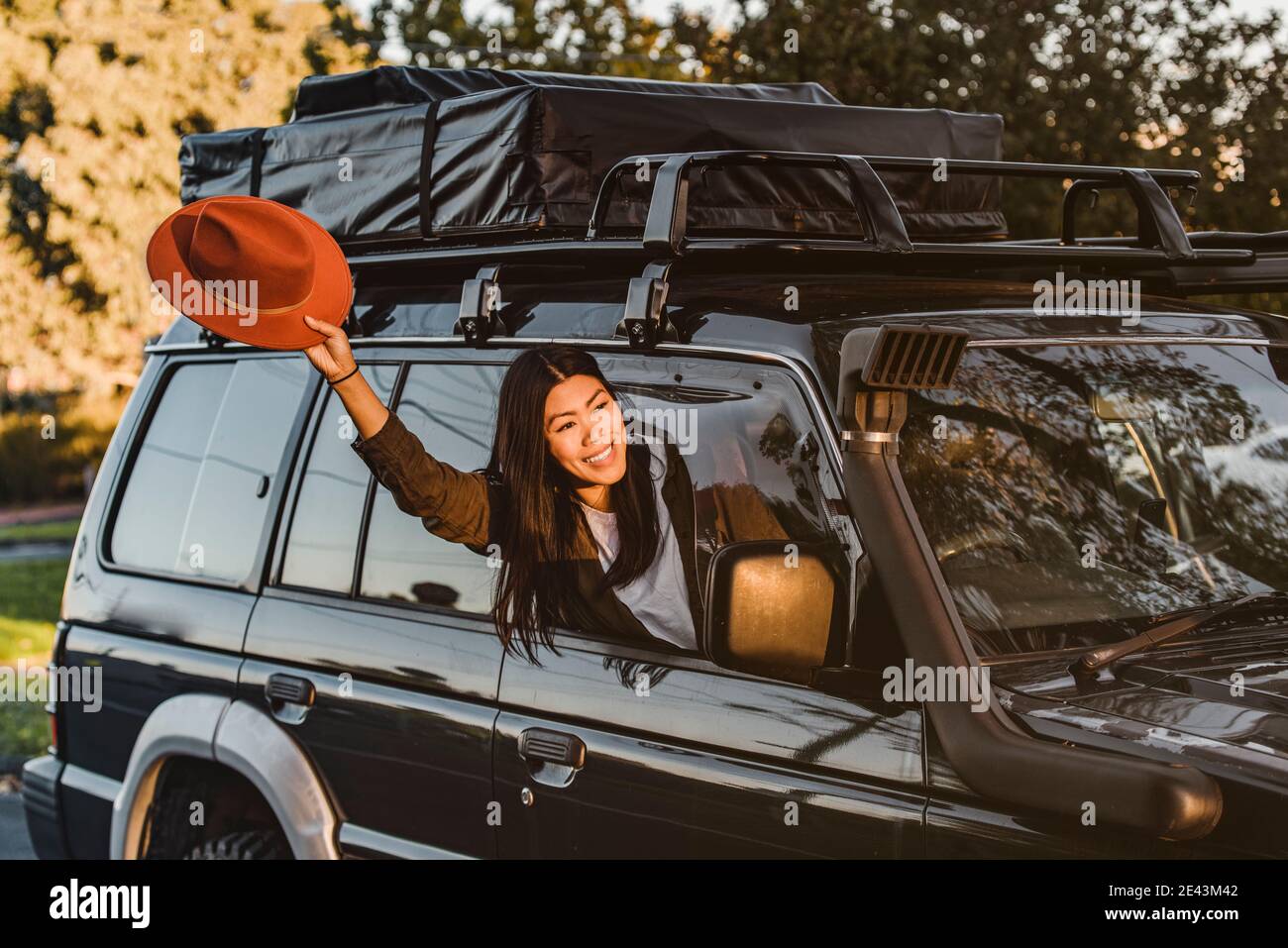 Une femme asiatique positive sort de la fenêtre de la voiture avec Bras tendu et main tendue tout en profitant de vacances en Australie Banque D'Images