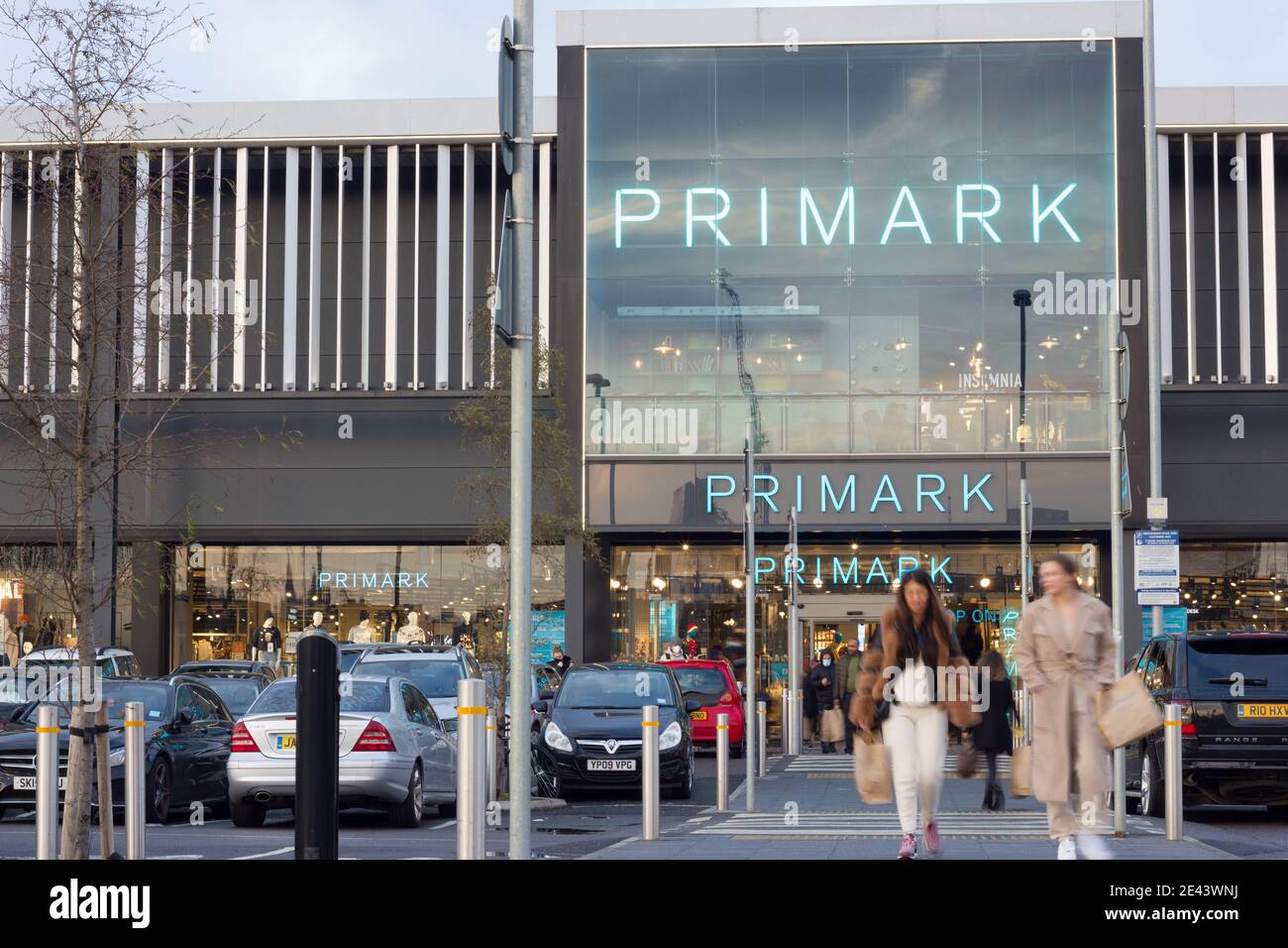 Les acheteurs de Primark avec des sacs de shopping à pied passent devant les voitures garées, Londres, Grand Londres Banque D'Images
