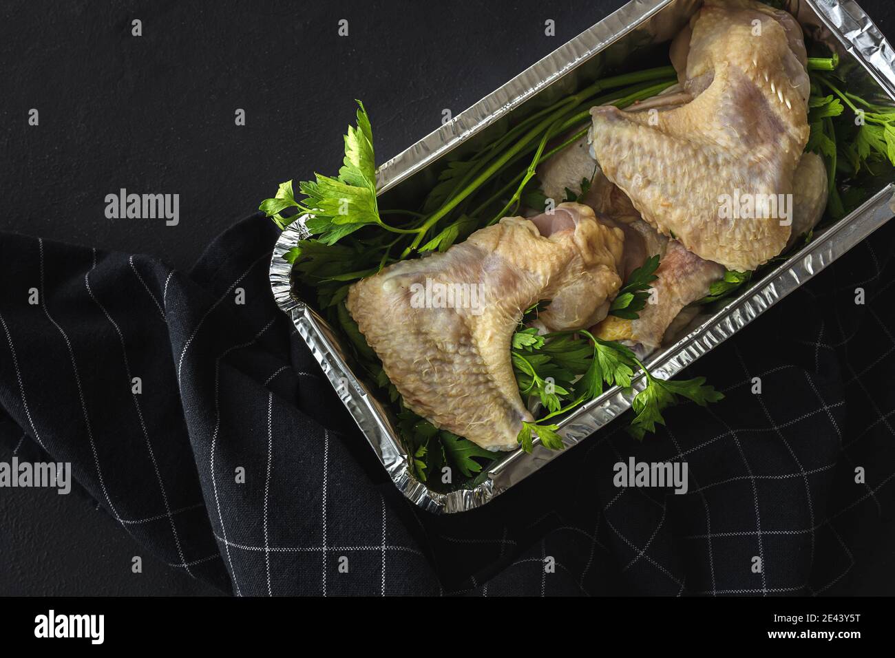 De ci-dessus, un récipient en aluminium pratique pour aller avec du poulet non cuit ailes et persil Banque D'Images