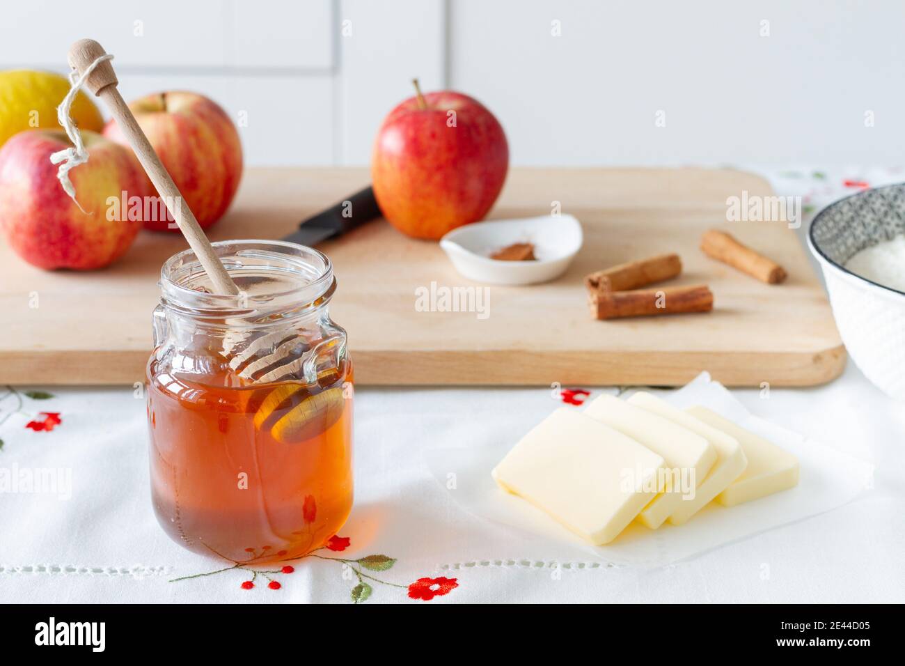 Bol en verre avec miel doux et cuillère placé près de la découpe embarquez avec une pomme mûre pour la préparation du dessert à la maison Banque D'Images