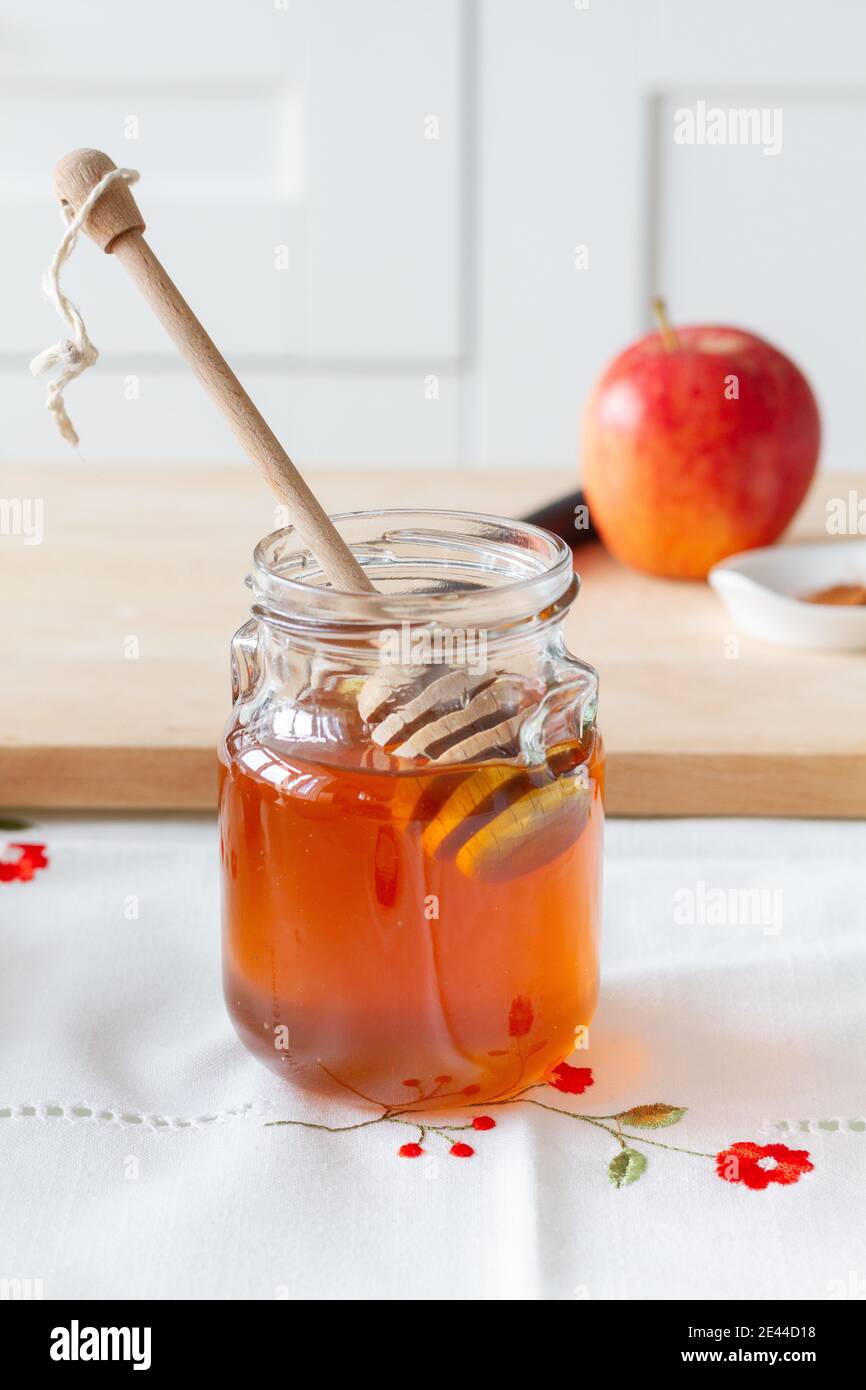 Bol en verre avec miel doux et cuillère placé près de la découpe embarquez avec une pomme mûre pour la préparation du dessert à la maison Banque D'Images