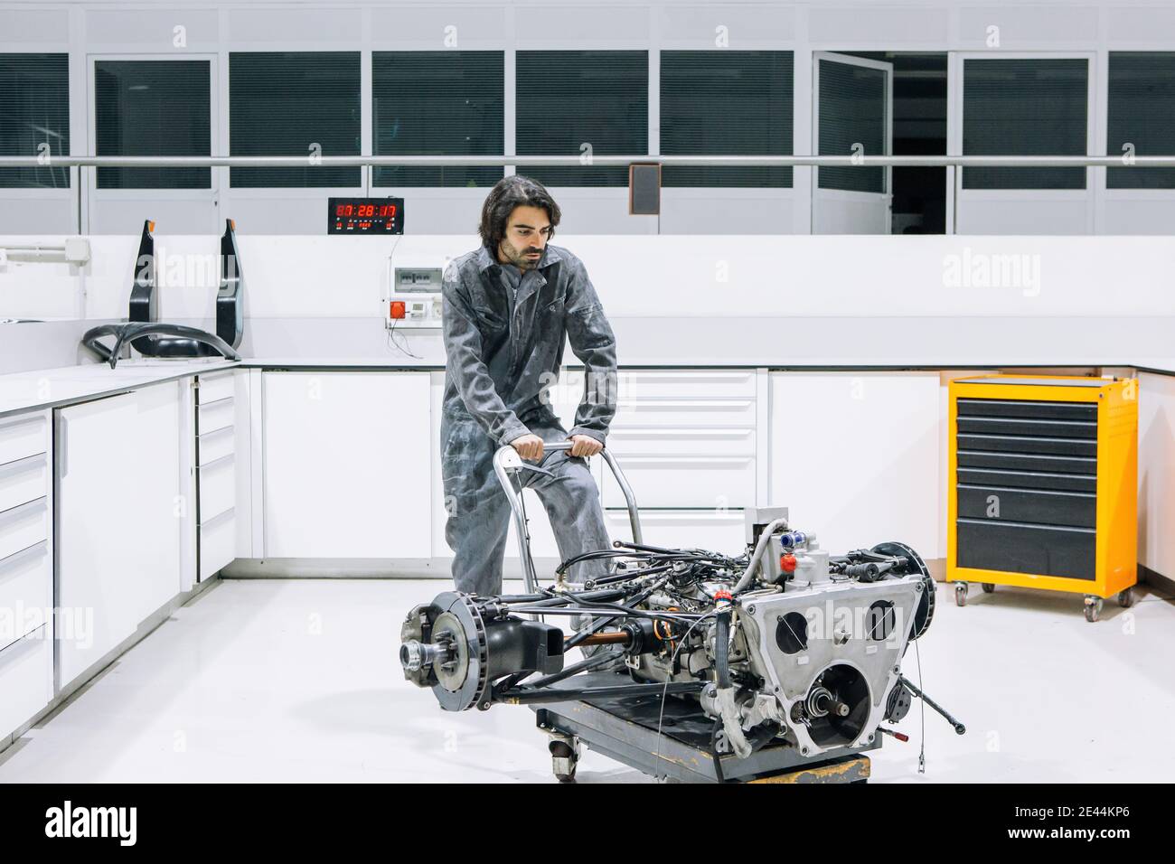 Homme technicien transportant une moto démontée sur un chariot pendant le travail atelier de réparation moderne Banque D'Images