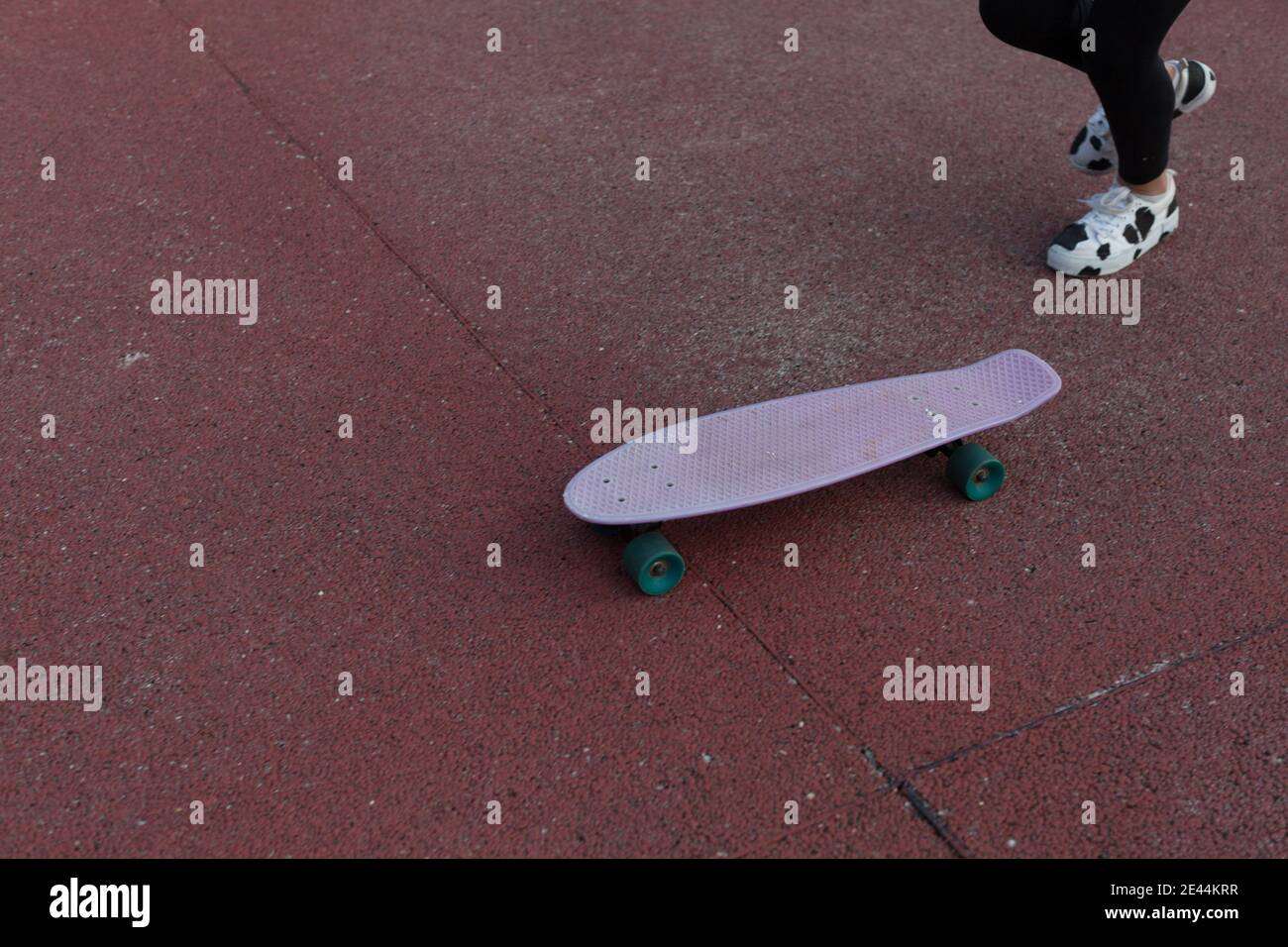 Une adolescente sans visage dans des baskets tendance marche près du panneau penny pendant l'entraînement sur terrain de sport Banque D'Images