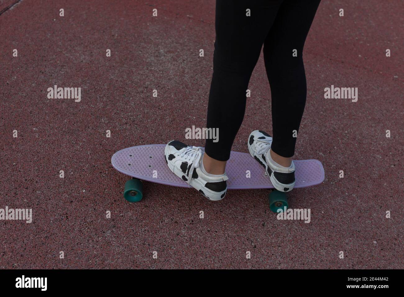 Une adolescente sans visage dans des baskets tendance à bord de penny pendant l'entraînement sur terrain de sport Banque D'Images