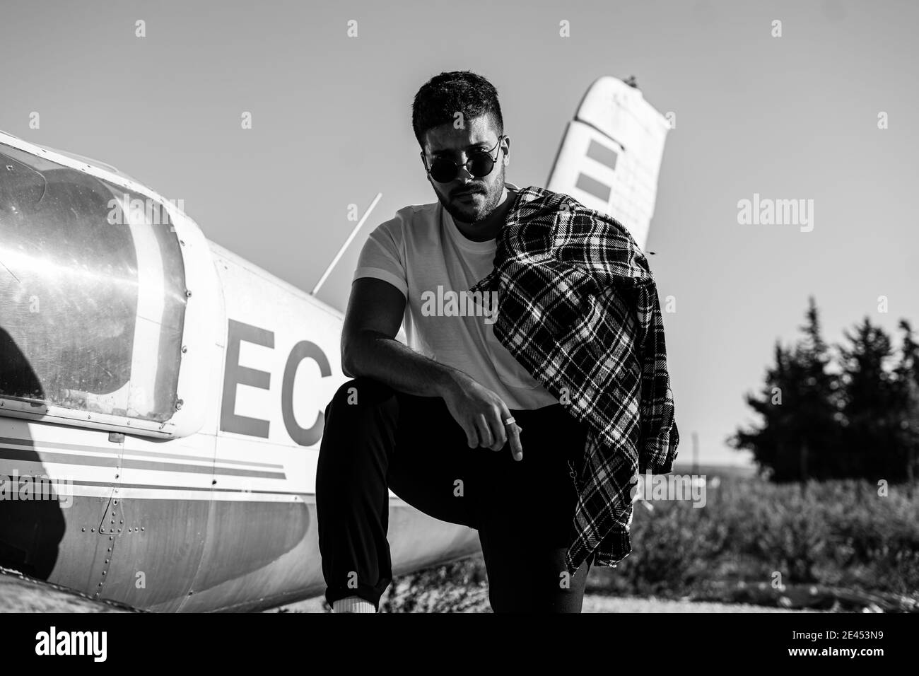 Prise de vue en niveaux de gris d'un homme caucasien froid debout près d'un avion accidenté Banque D'Images