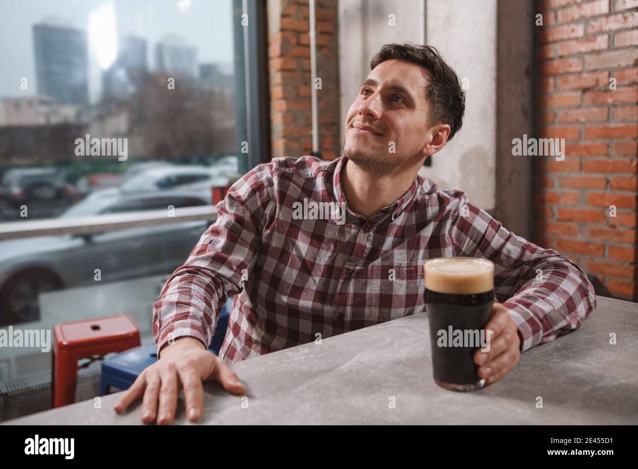 Joyeux jeune homme souriant, regardant la télévision au pub de bière, salle de copie Banque D'Images