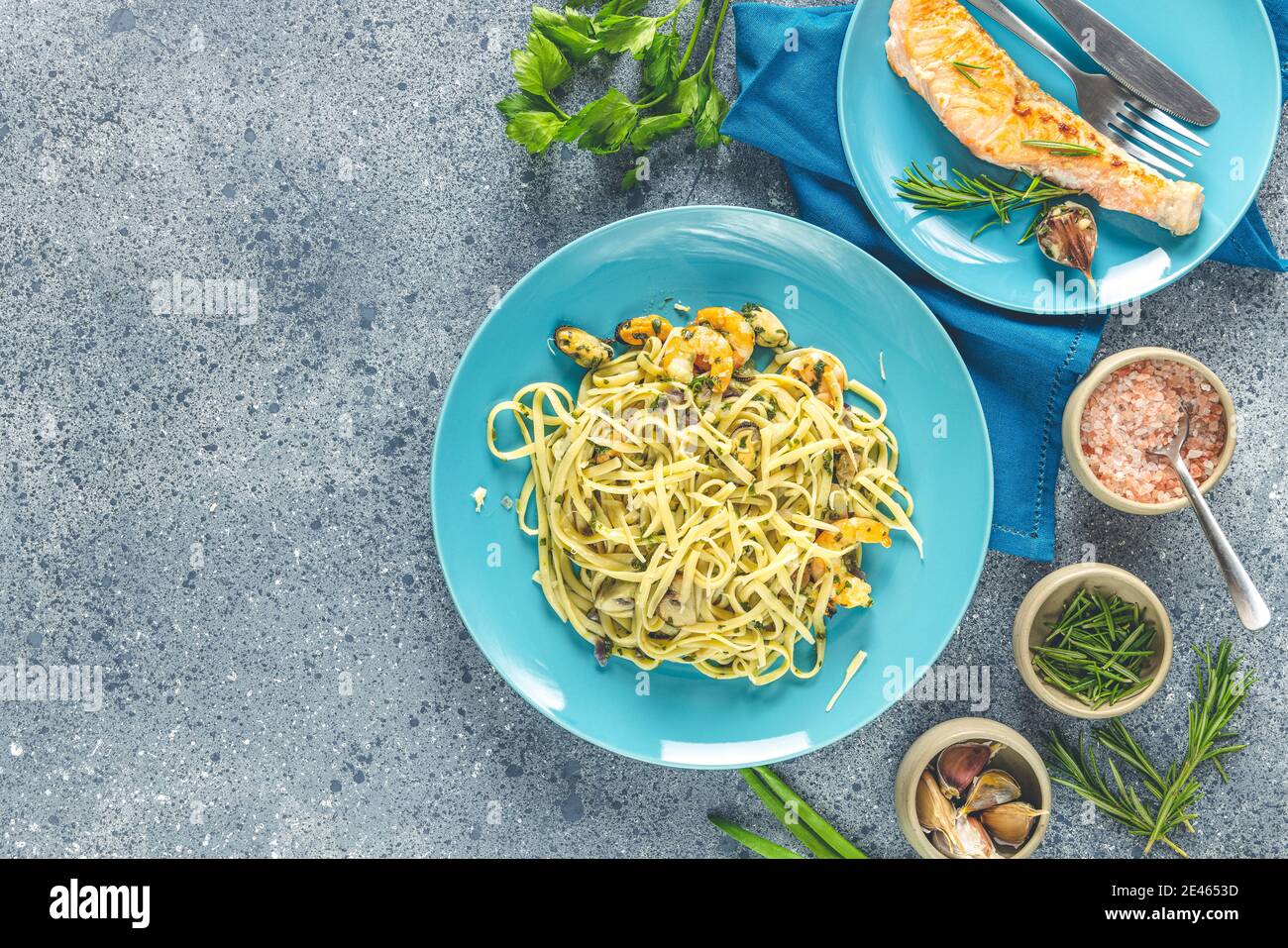 Pâtes linguine aux champignons, crevettes et moules de fruits de mer, fromage et herbes, en plaque de céramique bleue sur une surface gris clair. Banque D'Images