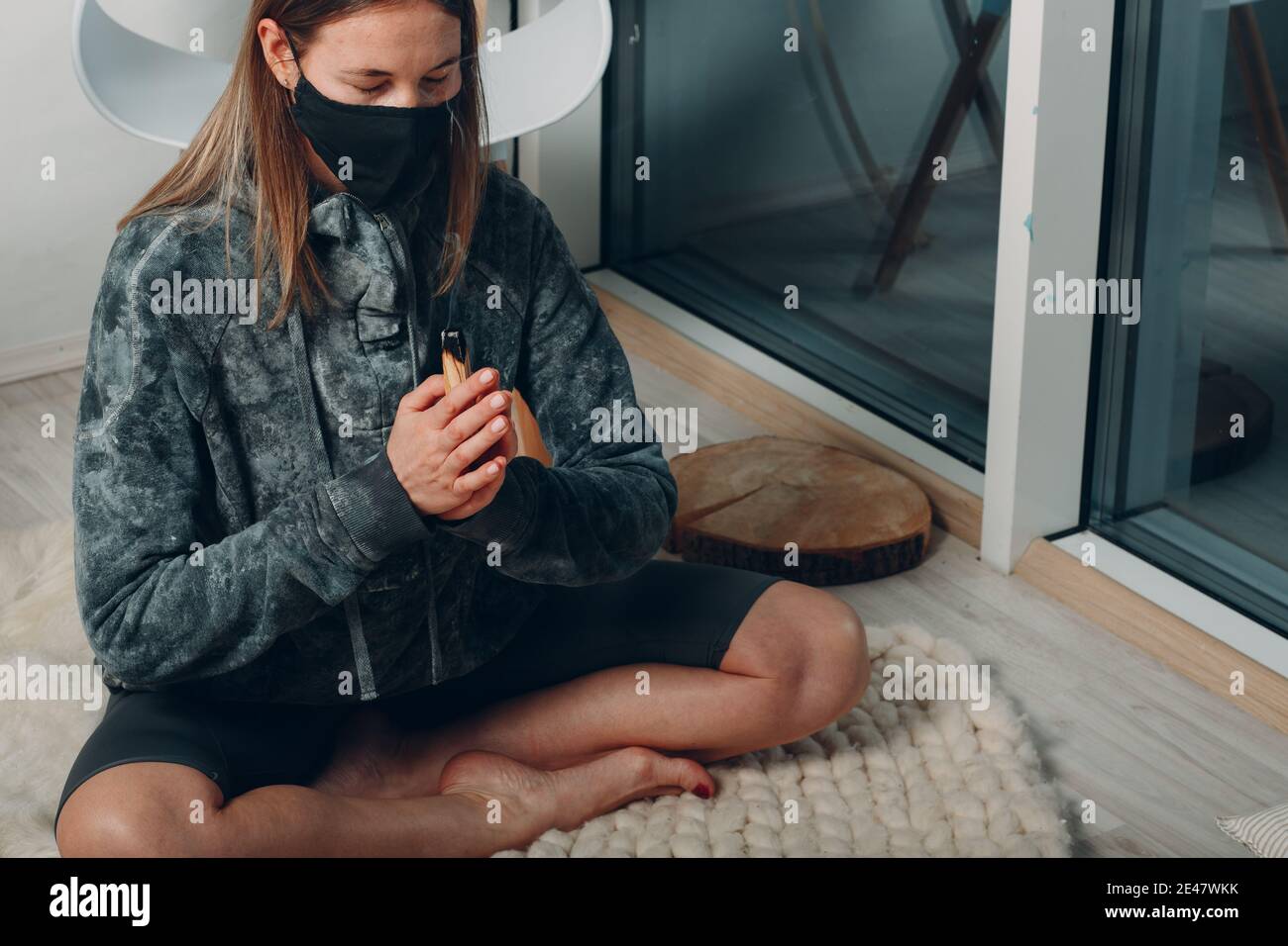 Adulte mature femme faisant du yoga dans le masque facial à la maison salon avec fumer palo santo bâton arbre. Bursera Graveolens Banque D'Images