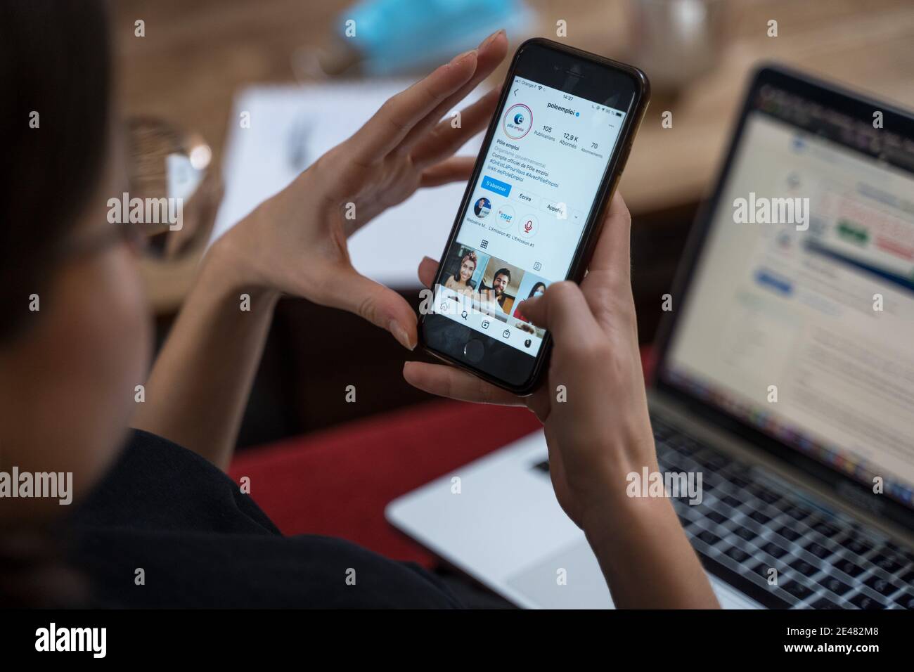 Une femme tient un téléphone portable devant un ordinateur portable Banque D'Images