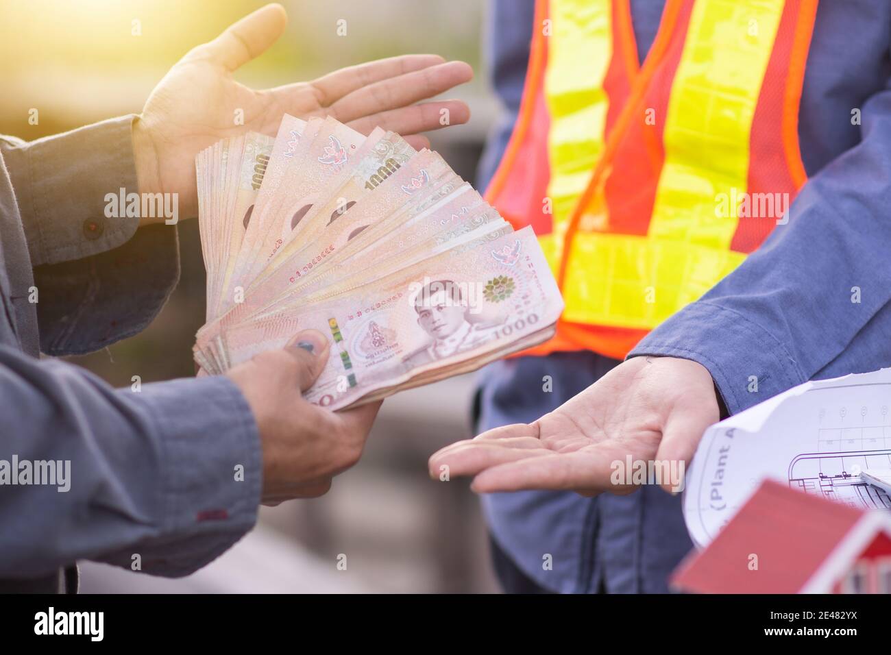 L'homme d'affaires paie le salaire de l'ingénieur constructeur dans la construction du site Banque D'Images