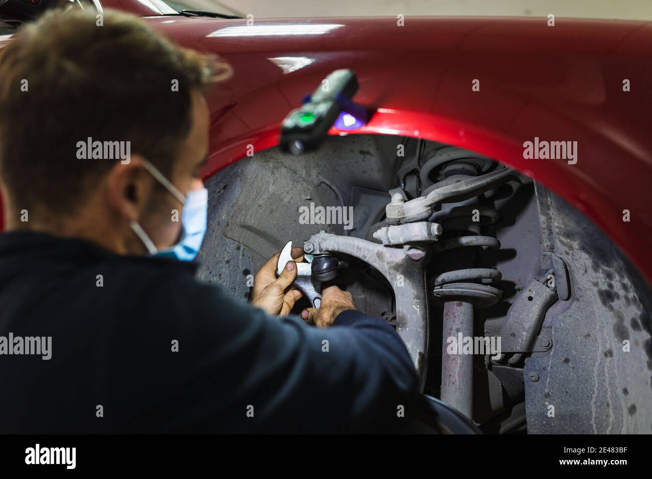 mécanicien répare la suspension de voiture. Concentrez-vous sur les mains. COVID 19 Banque D'Images