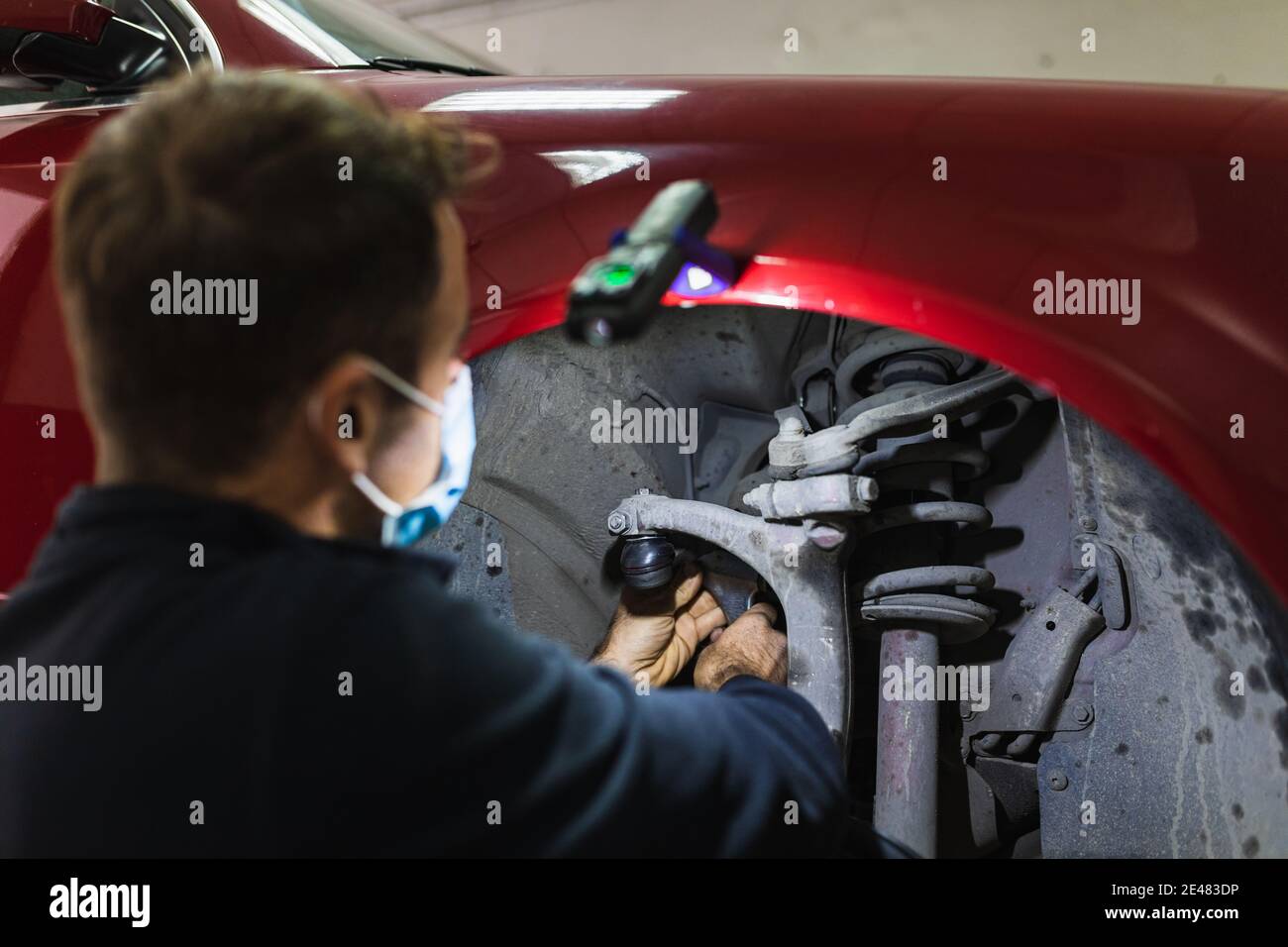 mécanicien répare la suspension de voiture. Concentrez-vous sur les mains. COVID 19 Banque D'Images