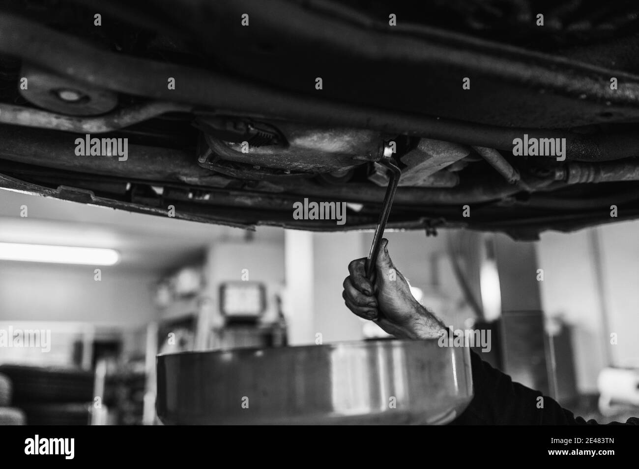 Mains d'un mécanicien changer l'huile de la voiture. Noir et blanc. Mécanique automobile concept Banque D'Images
