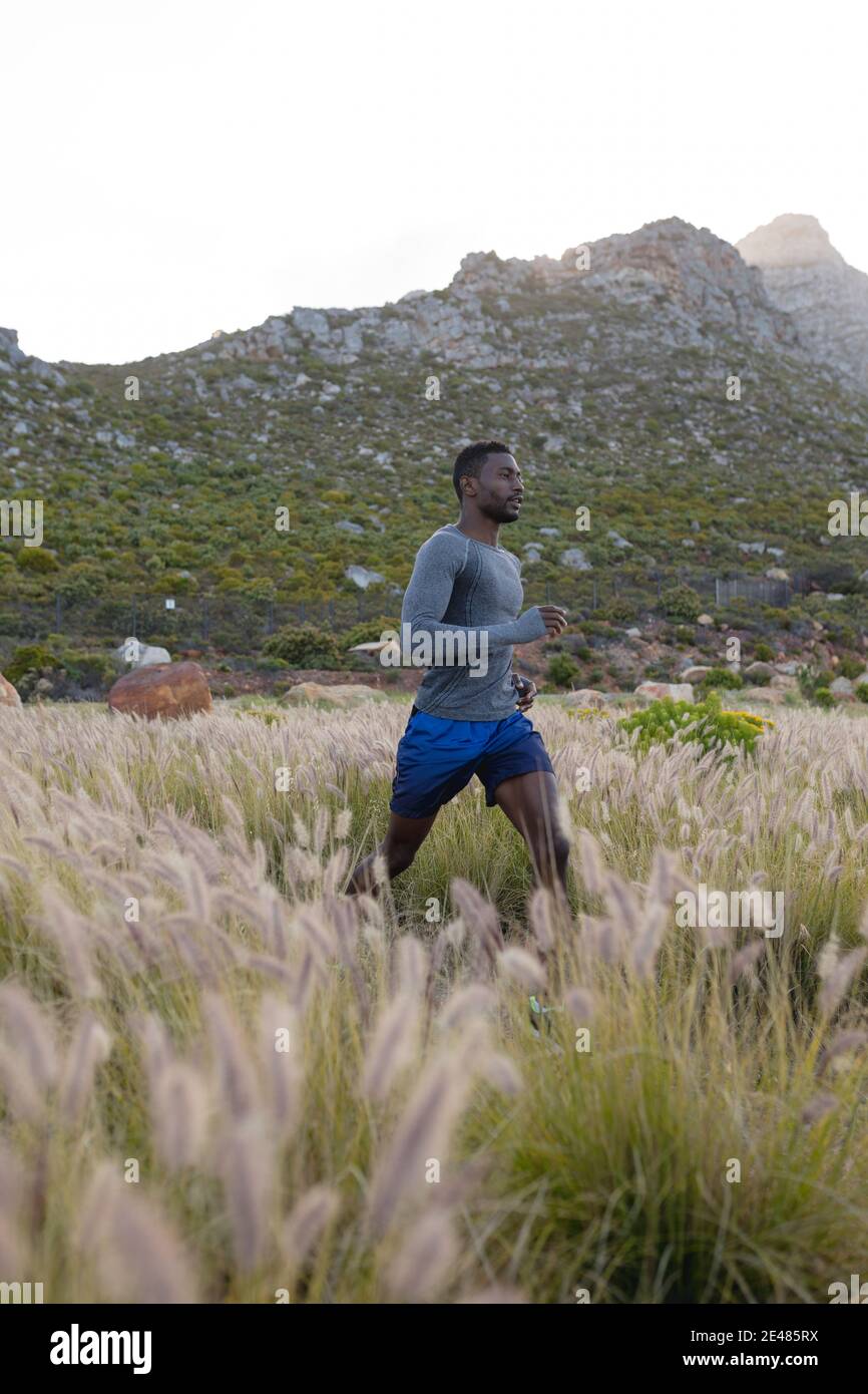 S'adapte à l'homme afro-américain dans des vêtements de sport qui traversent une grande herbe Banque D'Images