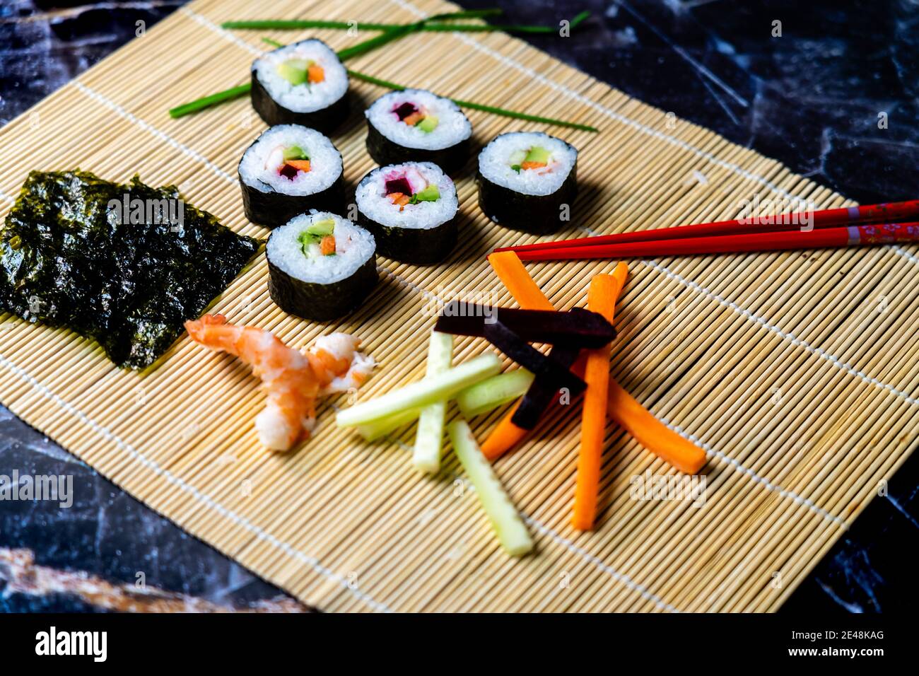 sushi maison traditionnel japonais maître faisant des petits pains maki sains avec crevettes concombres carottes poisson Banque D'Images