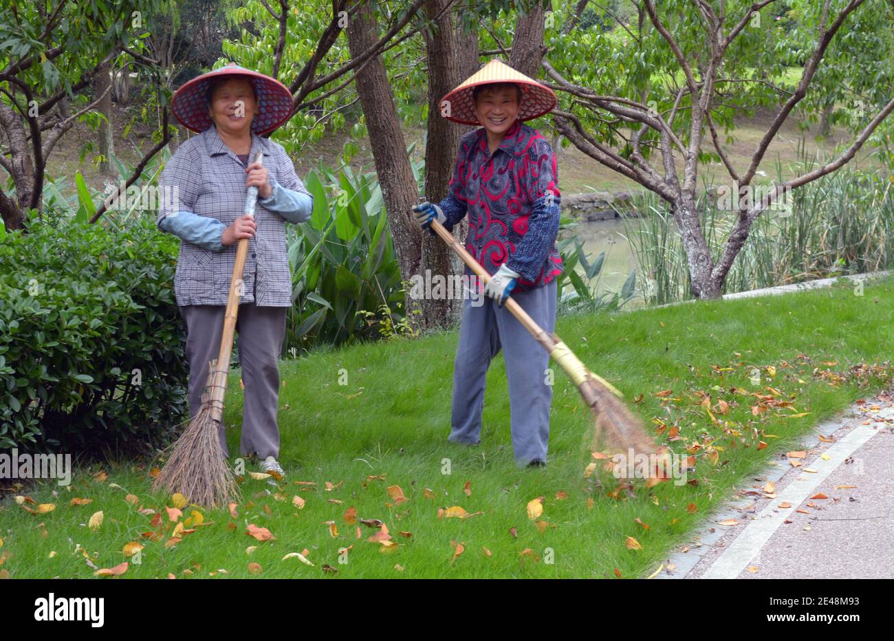 2 femmes de nettoyage et de nettoyage des feuilles dans un parc partager un sourire et rire avec moi que je prends leur photo. Banque D'Images