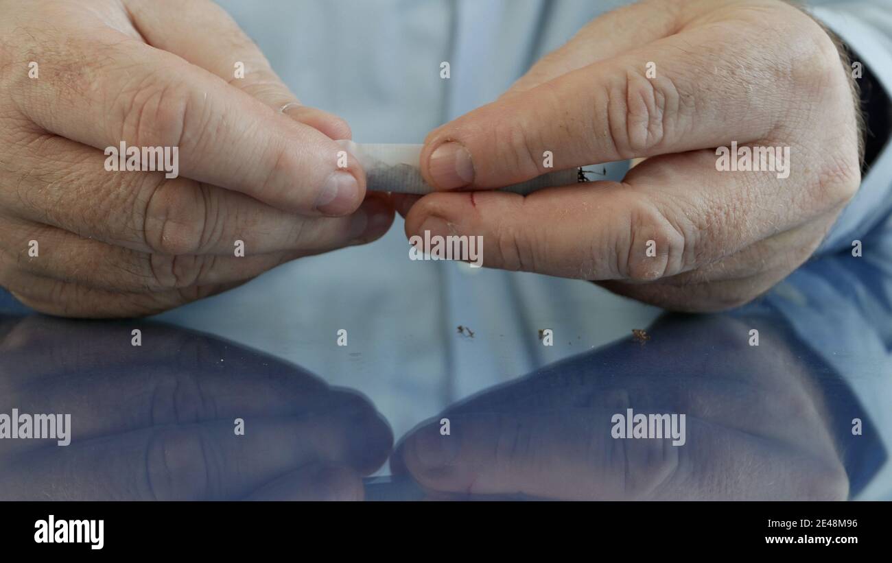 Fume rouler une cigarette faite à la main en utilisant du papier à cigarettes un filtre et du tabac Banque D'Images