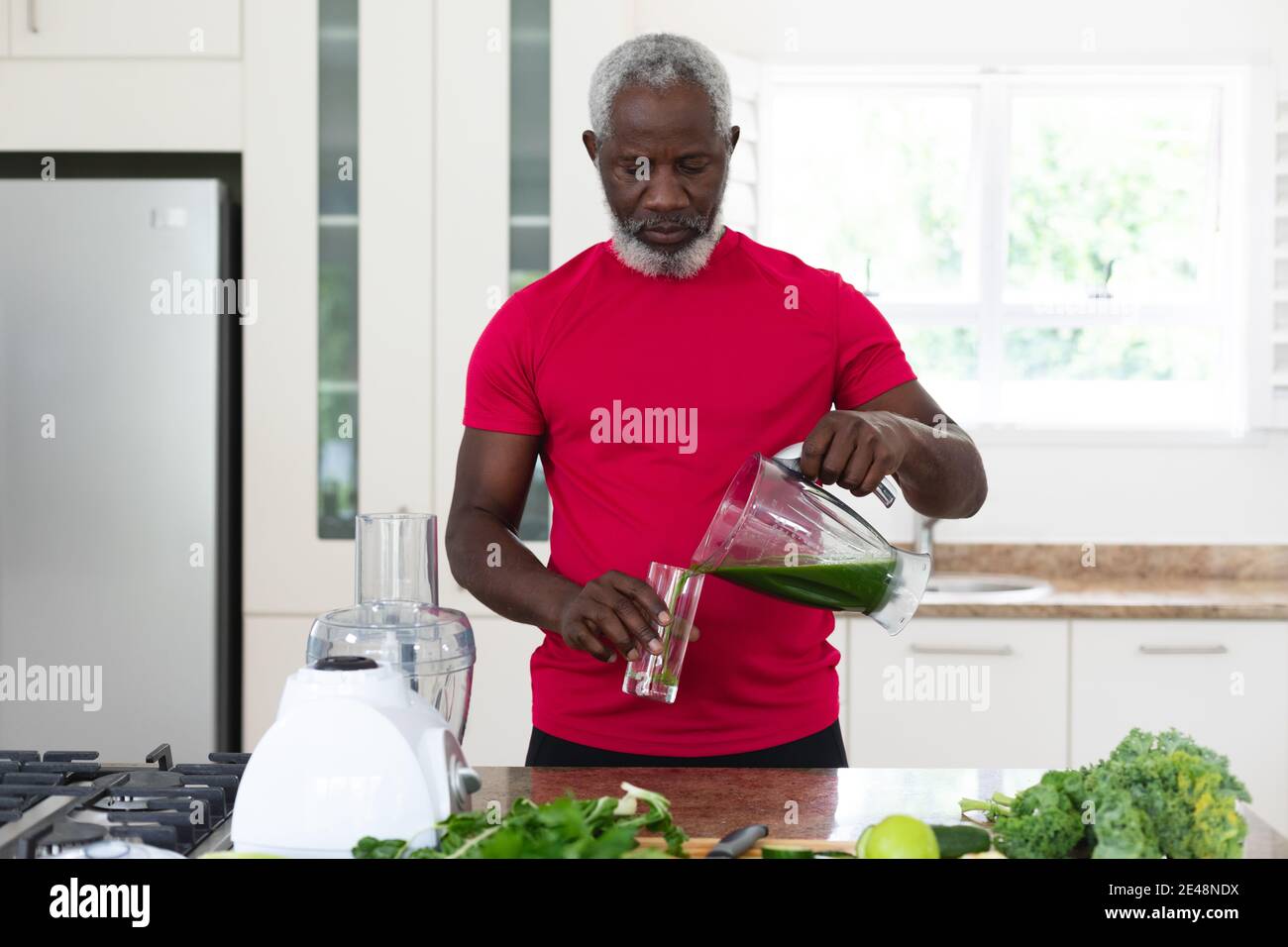 Homme afro-américain senior versant des fruits et des légumes boisson santé dans un verre Banque D'Images