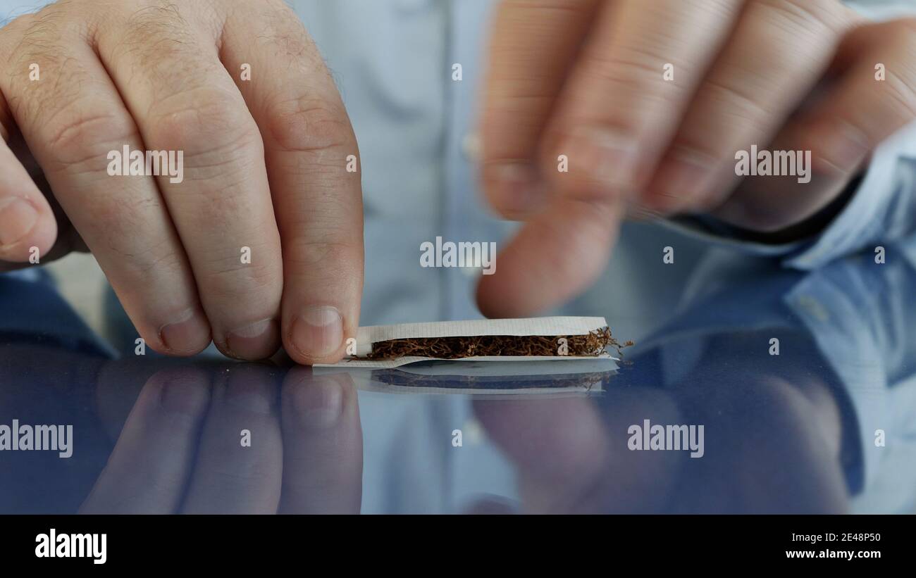 Fume rouler une cigarette faite à la main en utilisant du papier à cigarettes un filtre et du tabac Banque D'Images