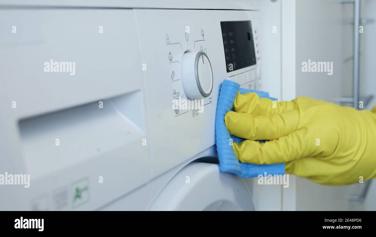 Homme mains porter des gants de protection blancs nettoie et désinfecte Le lave-linge Banque D'Images