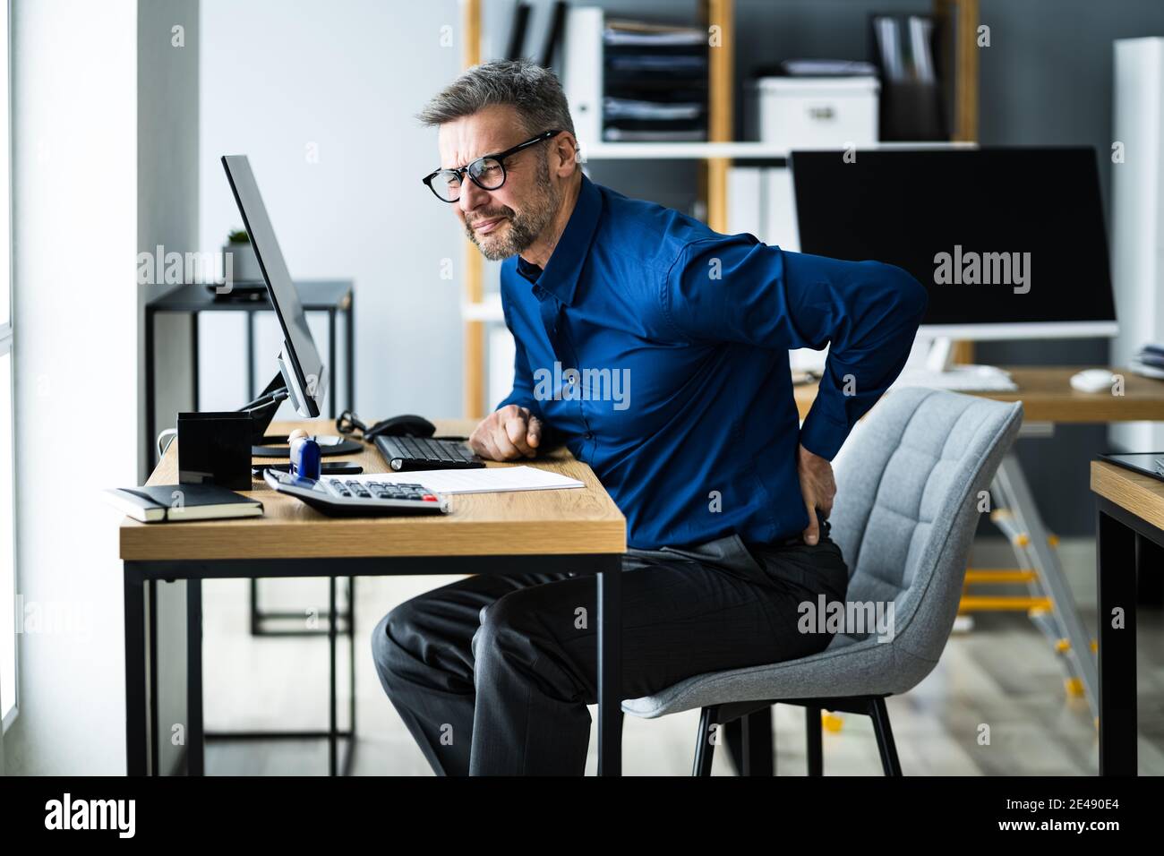 Mal de dos mauvaise posture. Homme utilisant un ordinateur Banque D'Images