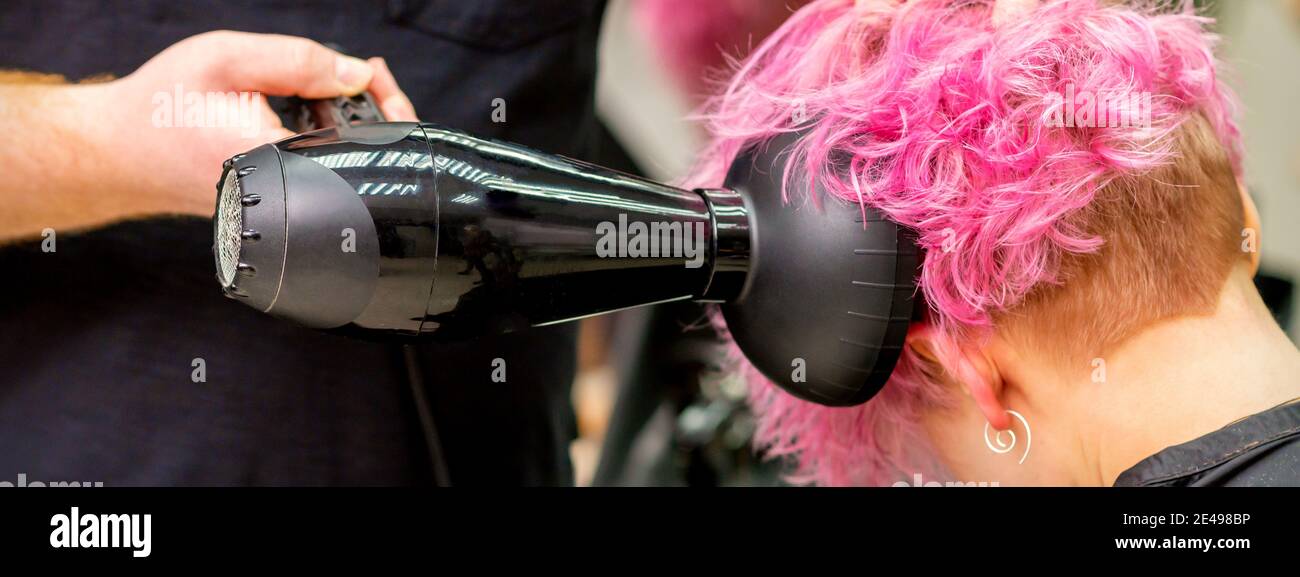 Gros plan du coiffeur séchage des cheveux courts roses ou rouges elle  comprend un sèche-cheveux dans un salon de beauté Photo Stock - Alamy