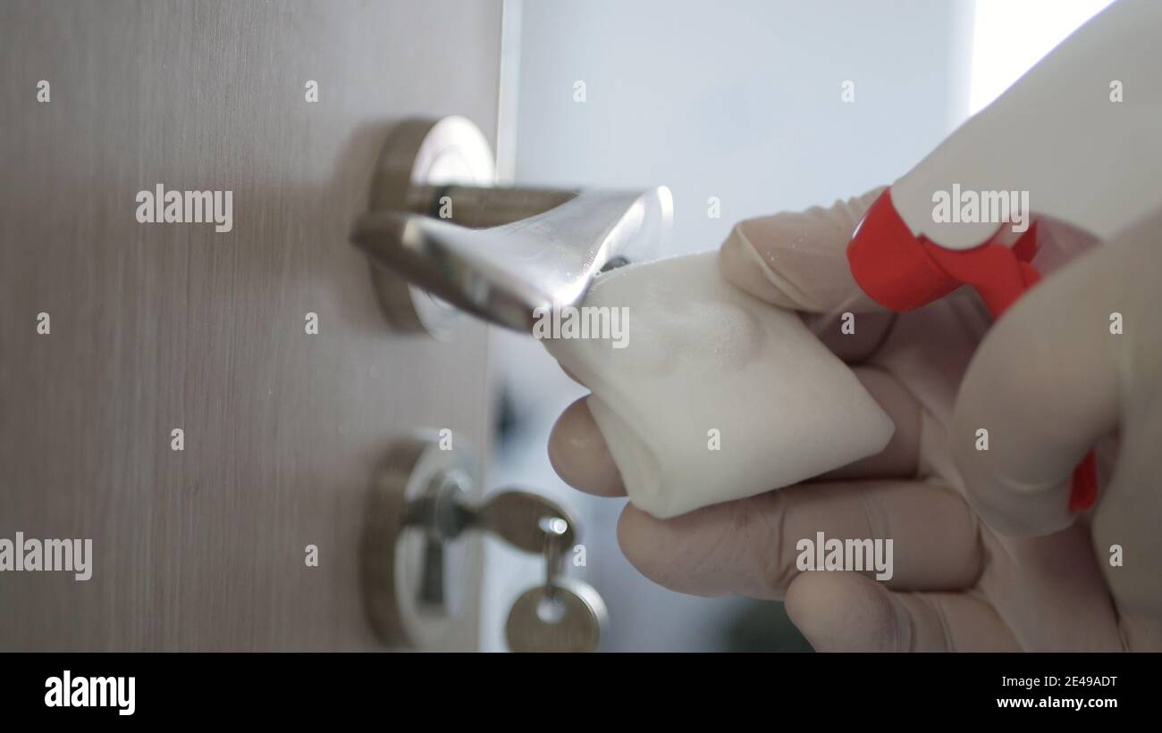 Homme portant des gants de protection désinfection à la maison d'une poignée de porte contre la contamination Covid-19 Banque D'Images
