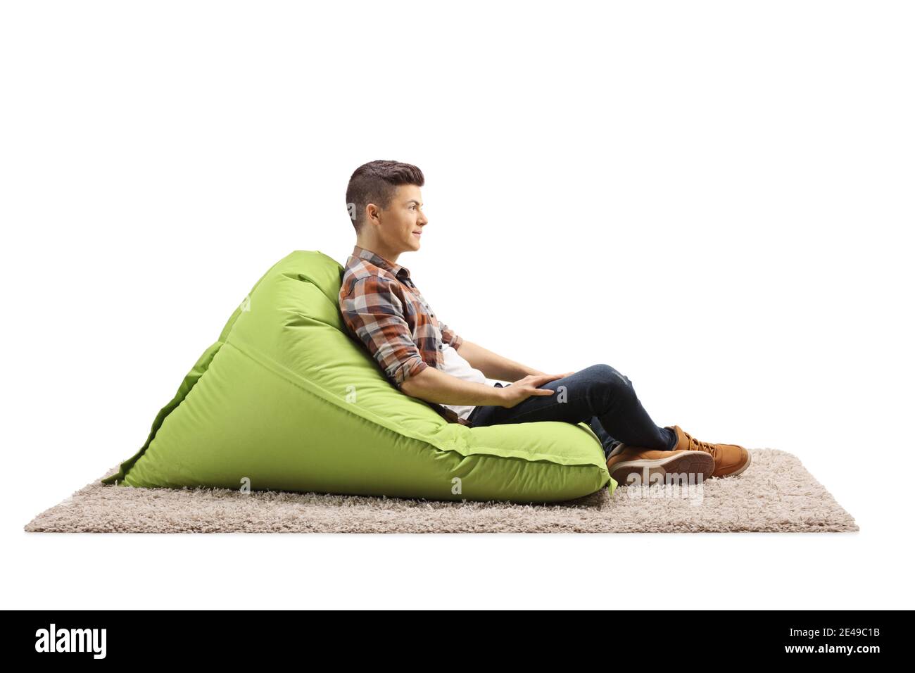 Photo de profil d'un gars assis sur un haricot vert fauteuil à sac isolé sur fond blanc Banque D'Images Photo de profil d'un gars assis sur un haricot vert fauteuil à sac isolé sur fond blanc Banque D'Images